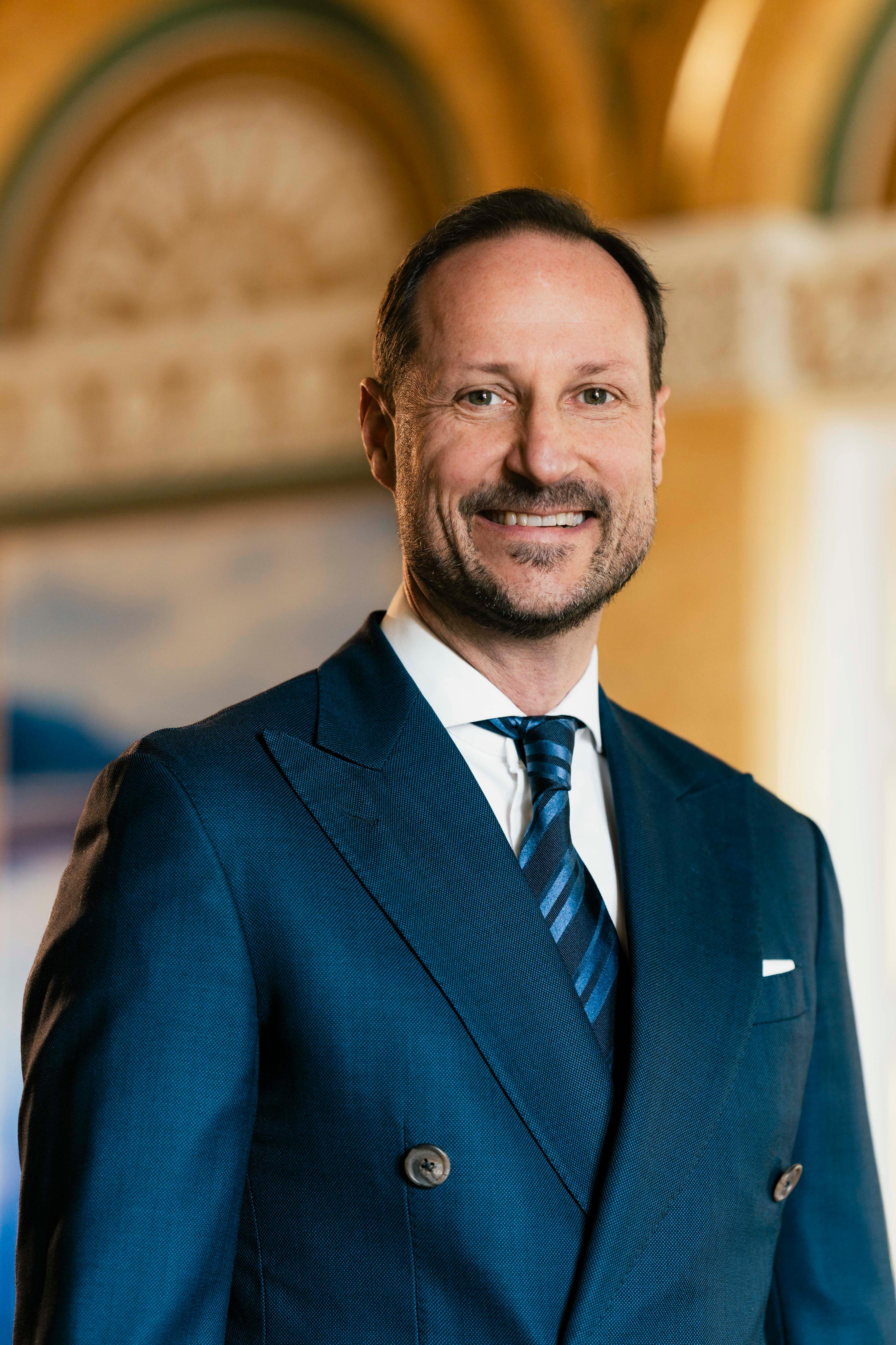 Portrett av Kronprins Haakon tatt i hvit skjorte mørkeblå dress med slips.