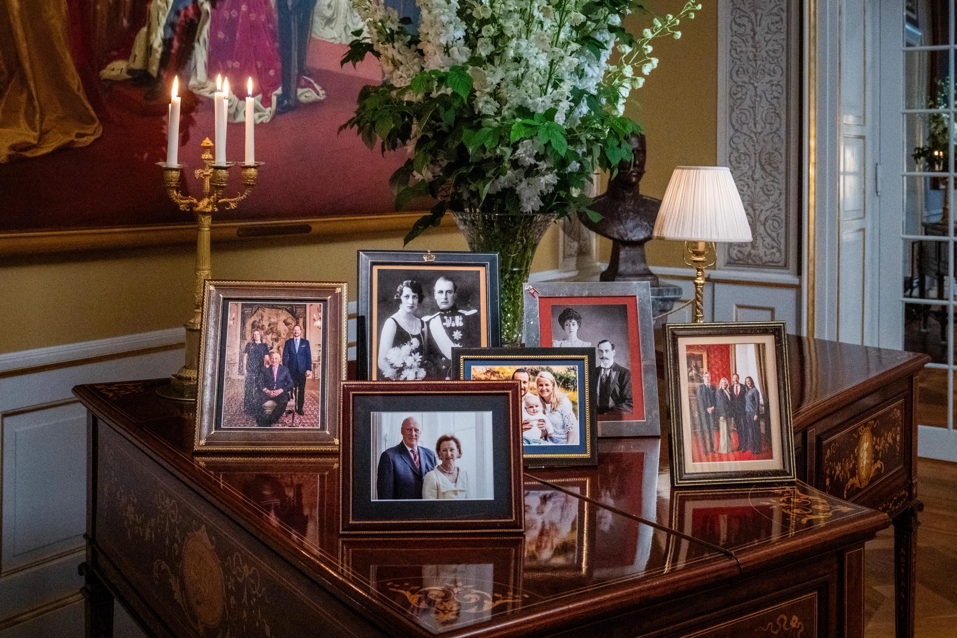 Det står syv innrammede fotografier på et vakkert intasja-dekorert mahogney-brunt klavér.