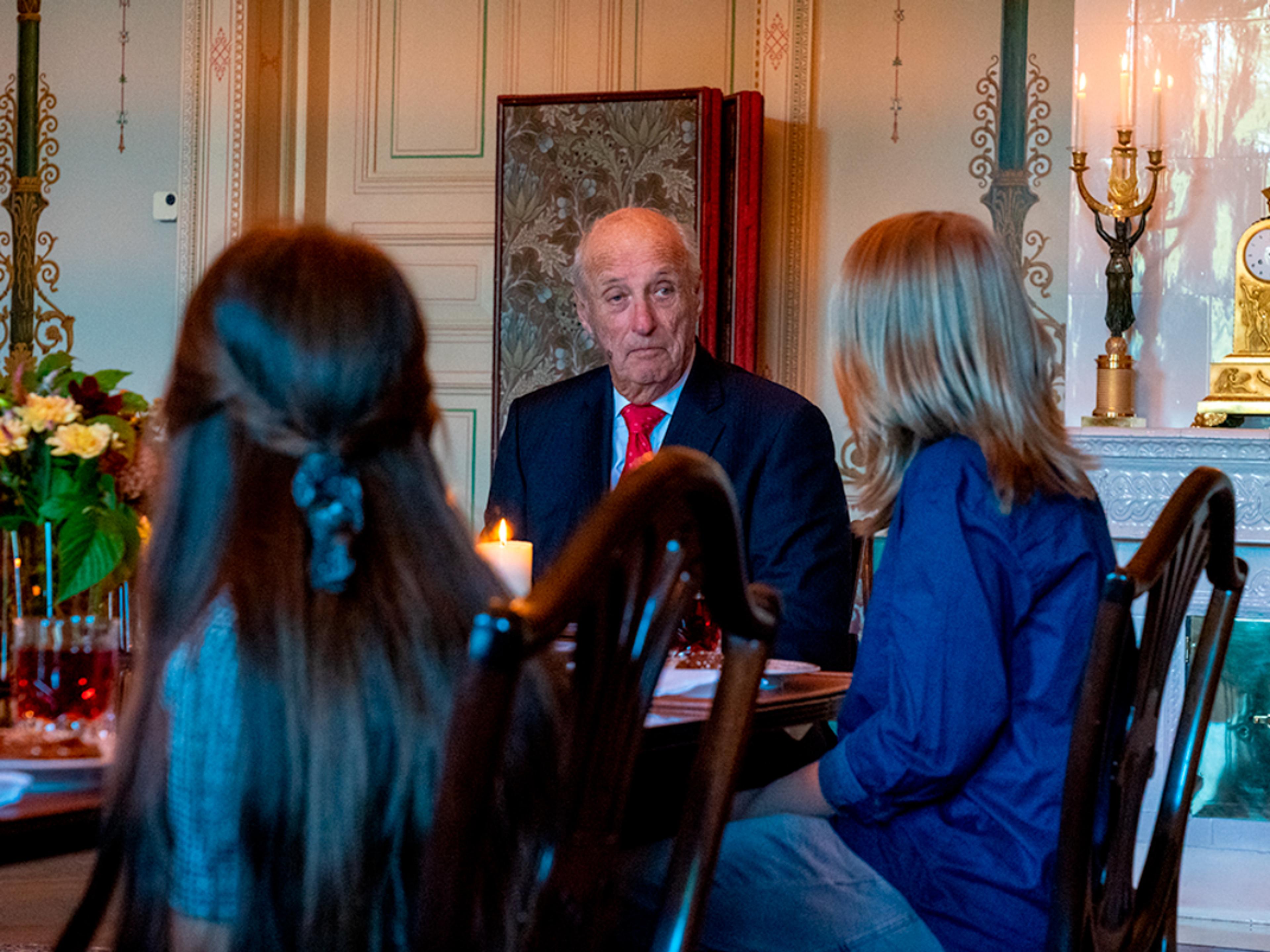 Kongen lytter til to barn som forteller om sine erfaringer. Barna sitter med ryggen til kameraet.