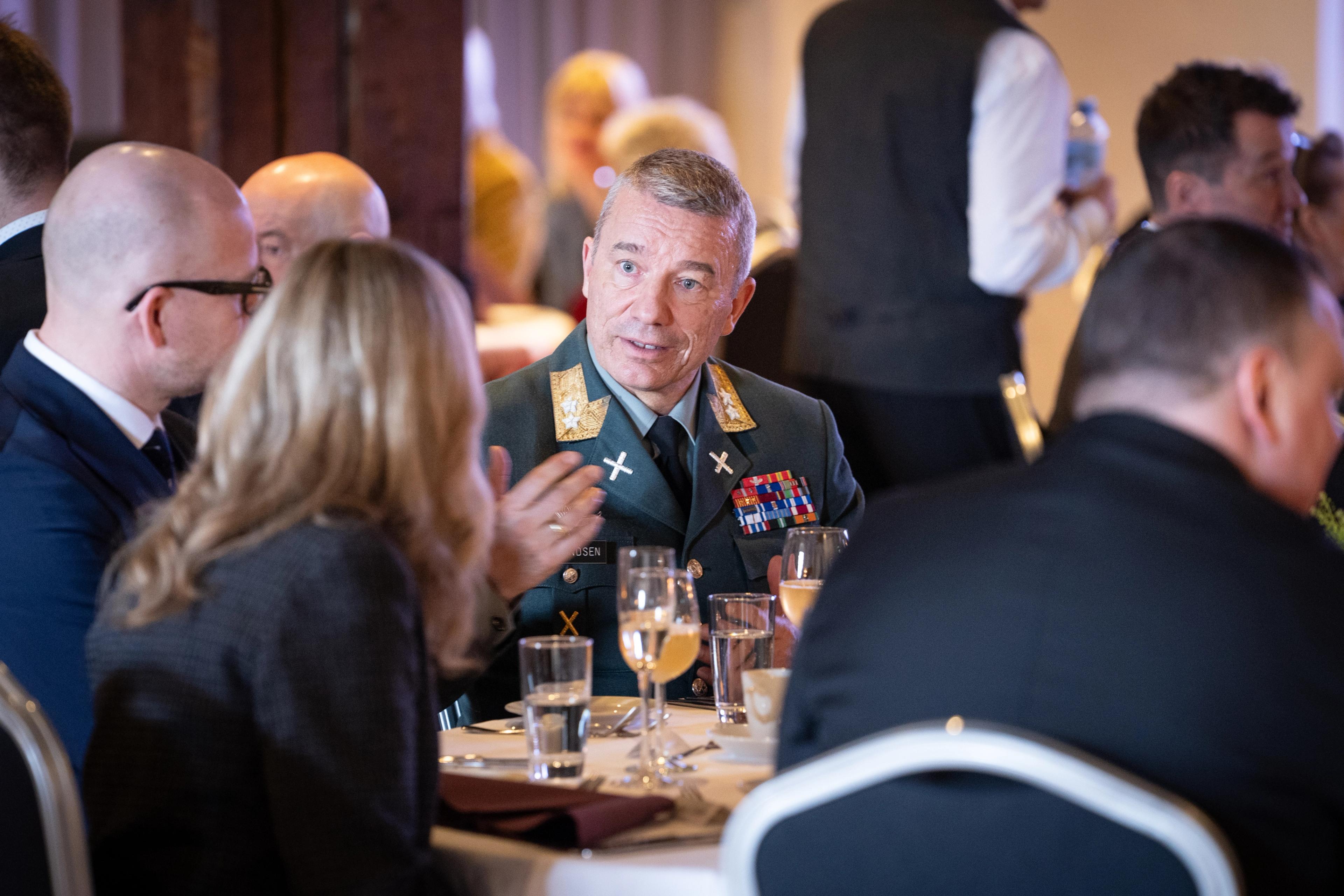 Sjef for Heimvernet i Hærens tjenesteuniform sitter ved et bord og snakker med andre deltakere.