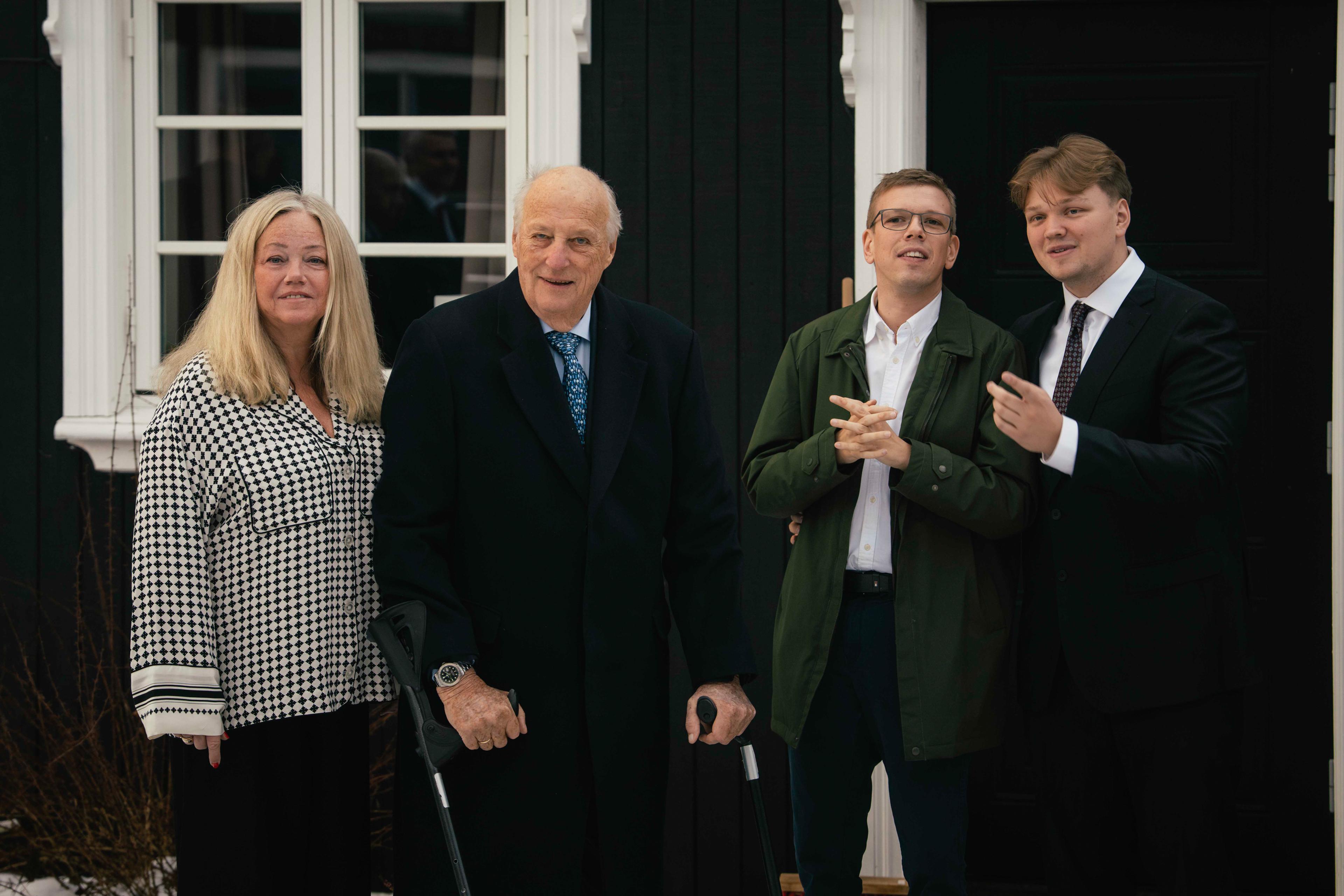 Kong Harald står på utsiden av huset, med Bjørg Gjestvang og barna Odin og Håkon ved siden av seg.