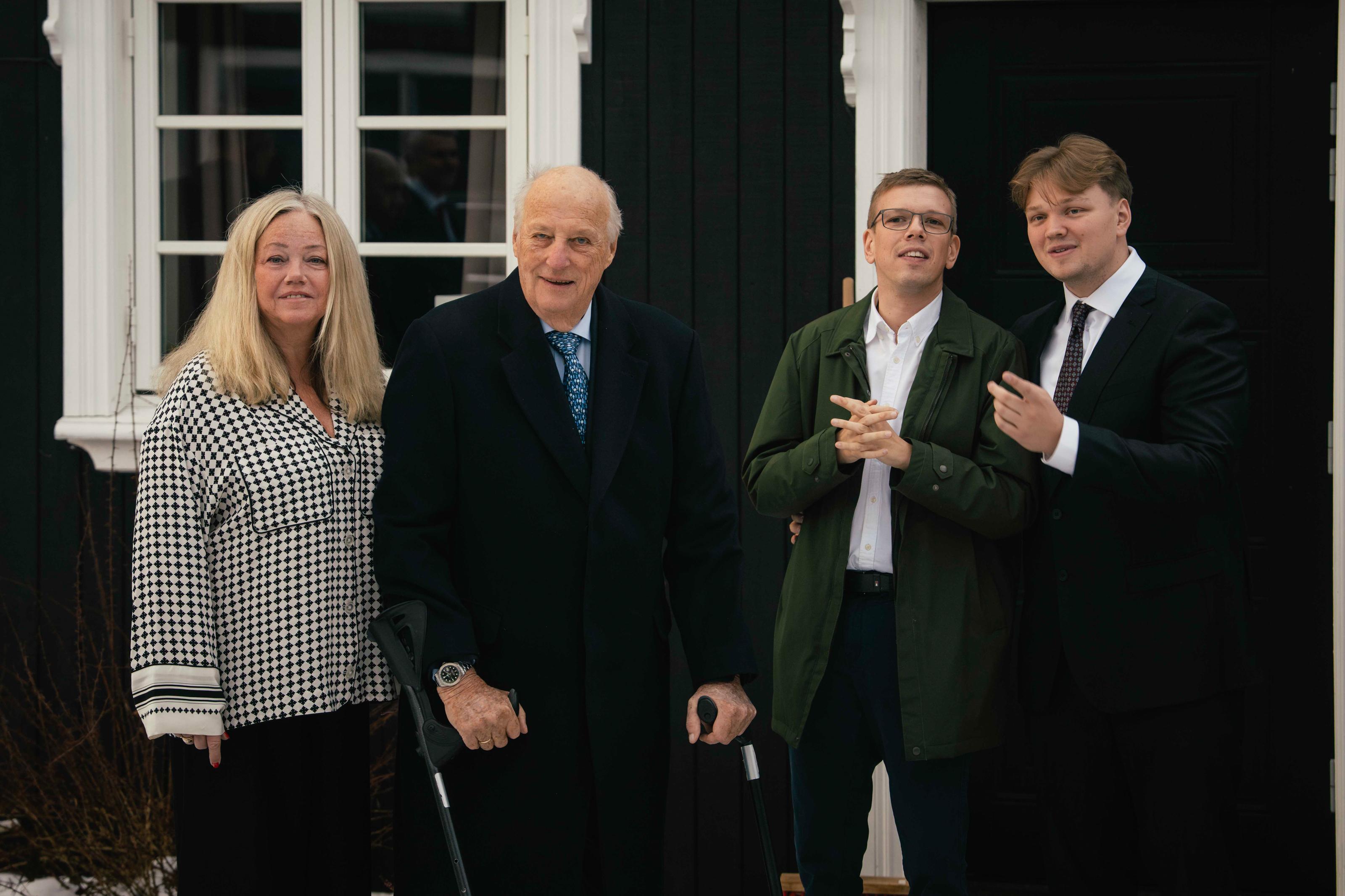 Kong Harald står på utsiden av huset, med Bjørg Gjestvang og barna Odin og Håkon ved siden av seg.