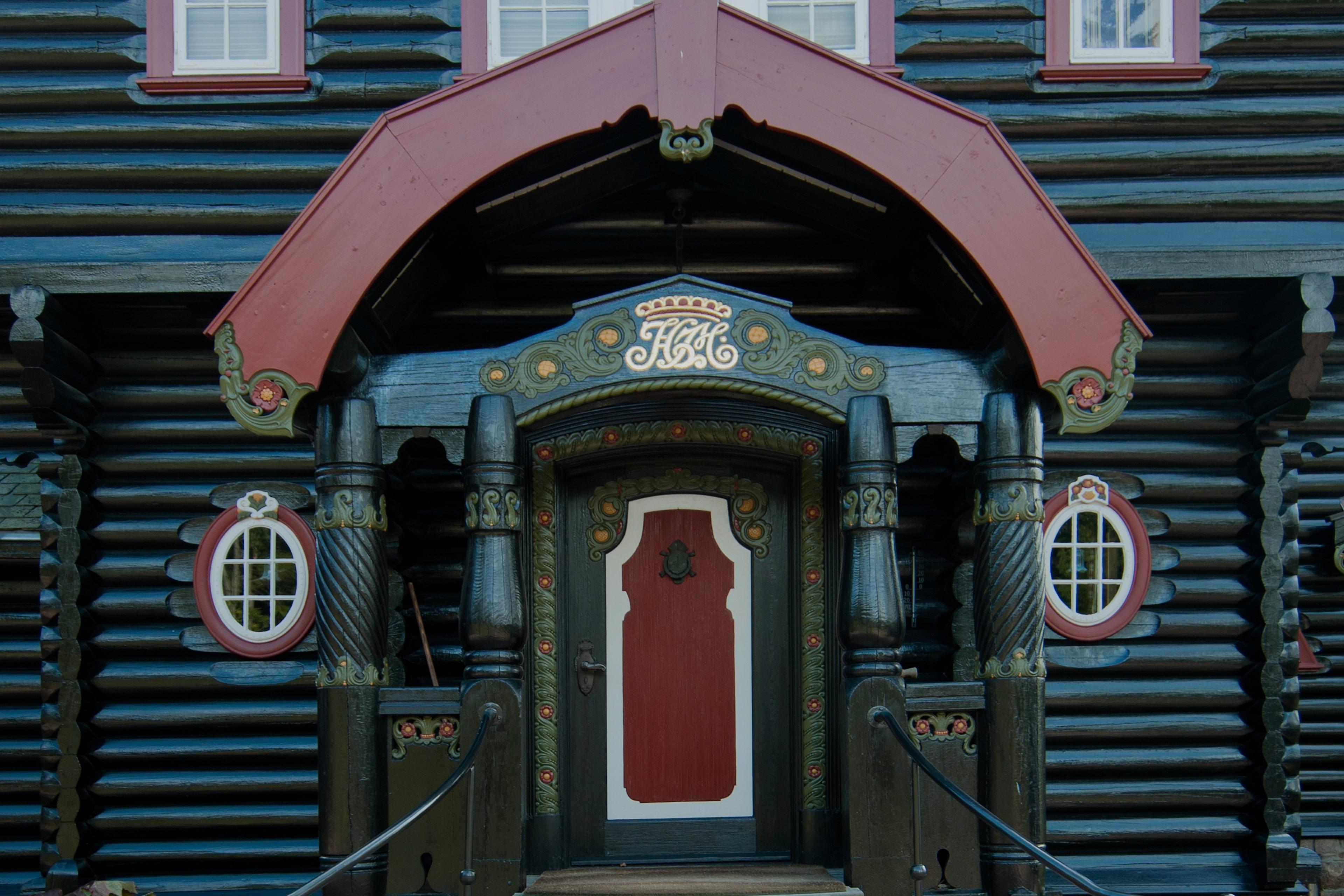 Hovedinngangen til det svartoljede huset i tømmer og skifer.