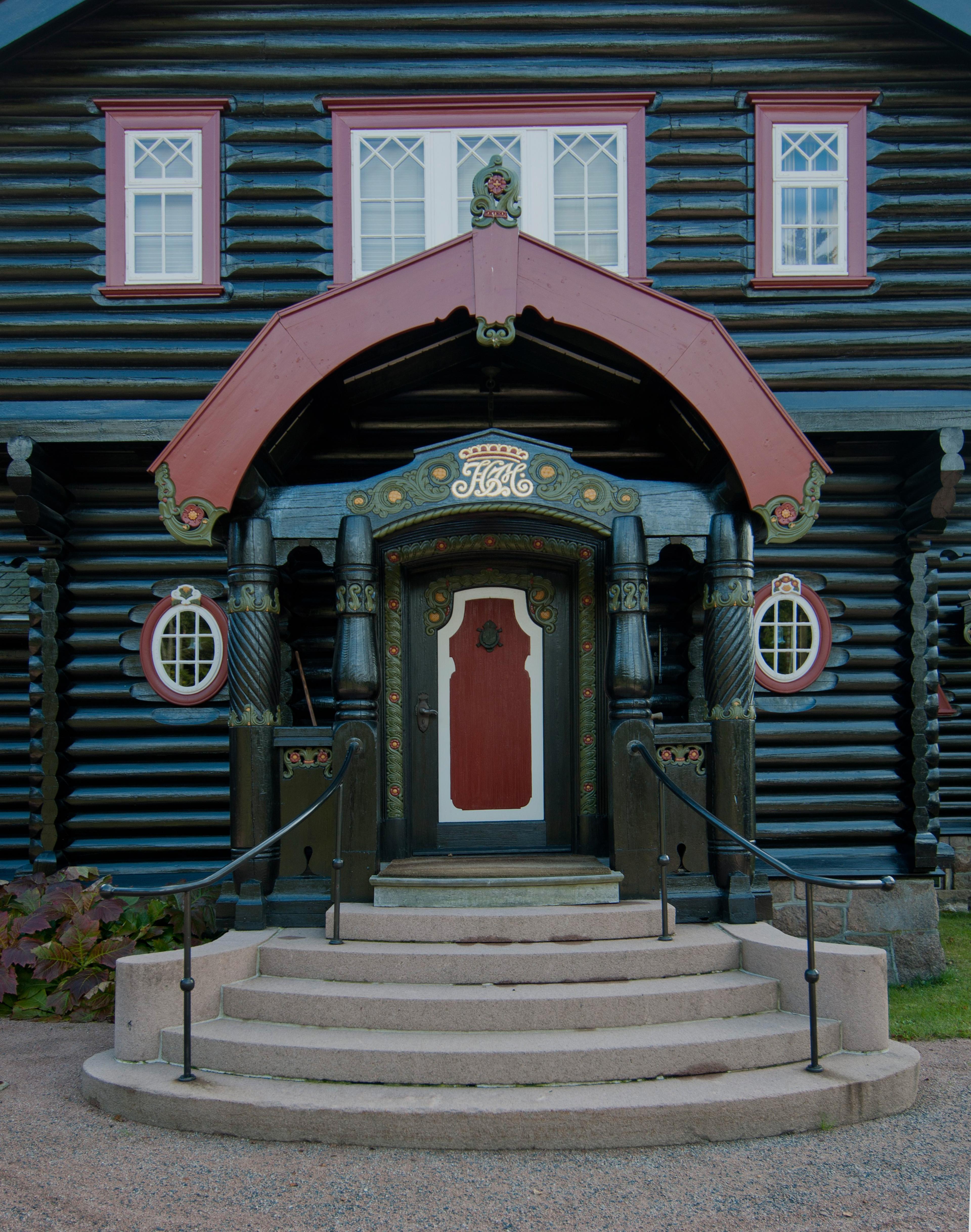 Hovedinngangen til det svartoljede huset i tømmer og skifer.