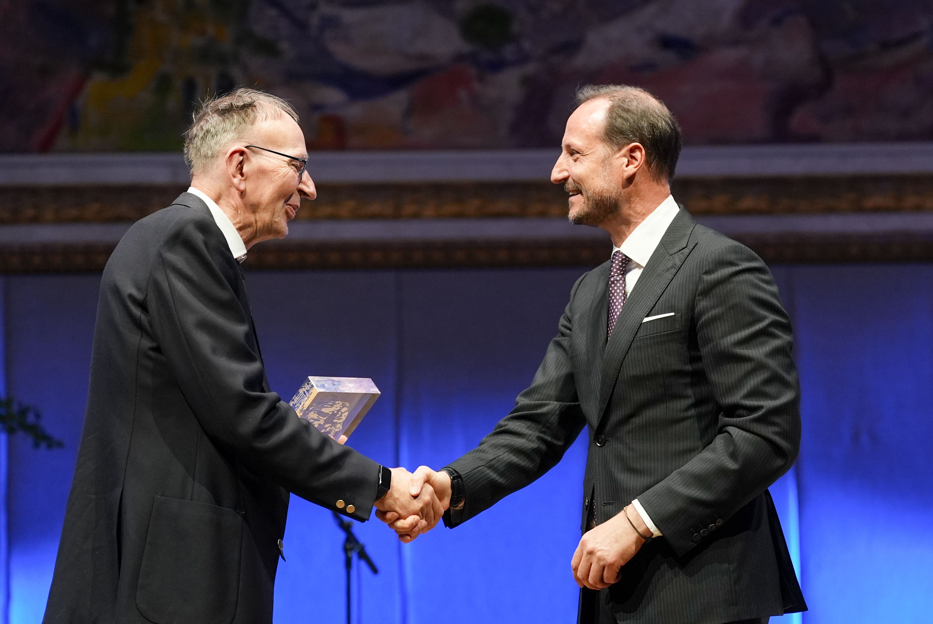 En smilende kronprins gratulerer vinneren på scenen.