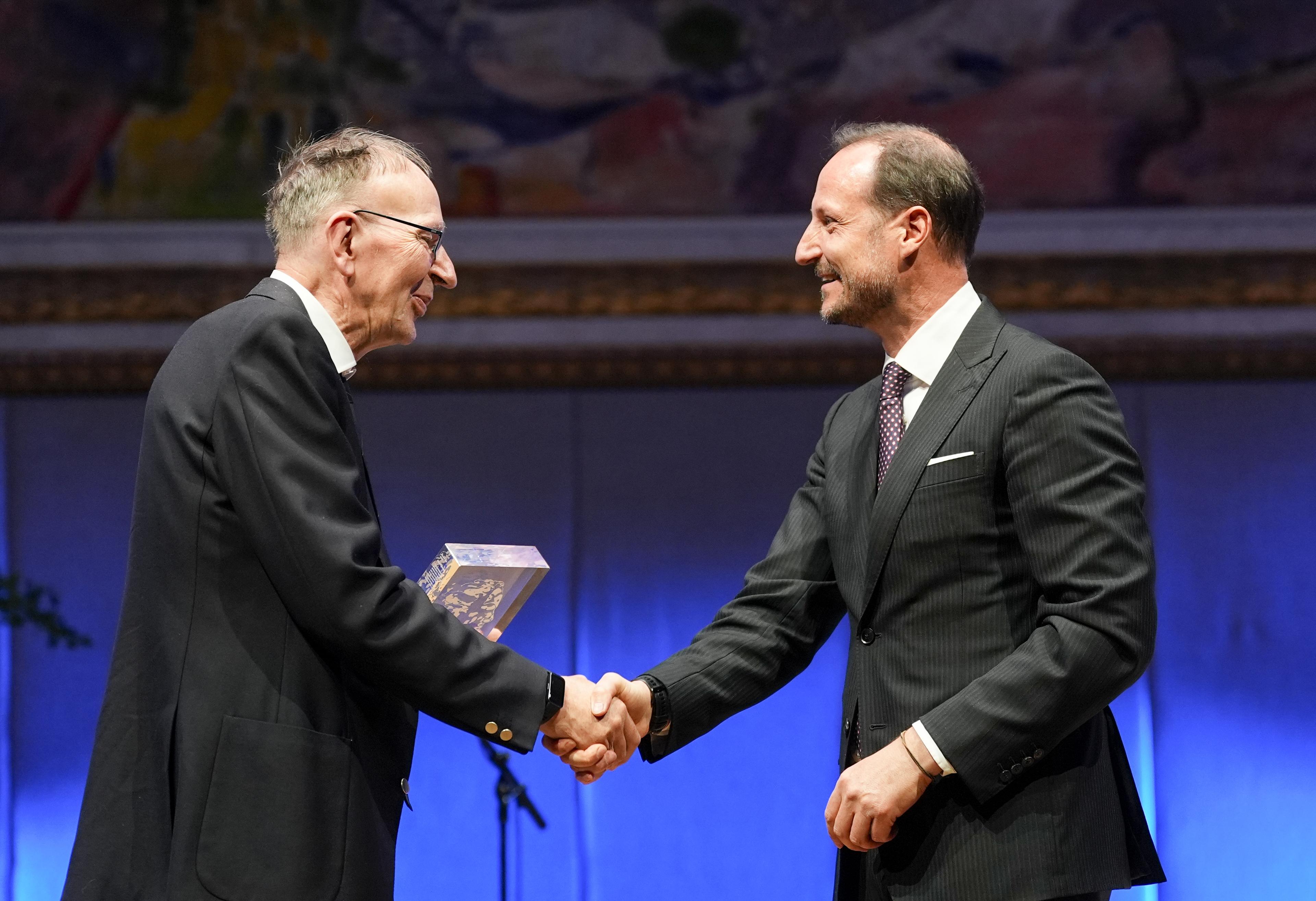 En smilende kronprins gratulerer vinneren på scenen.