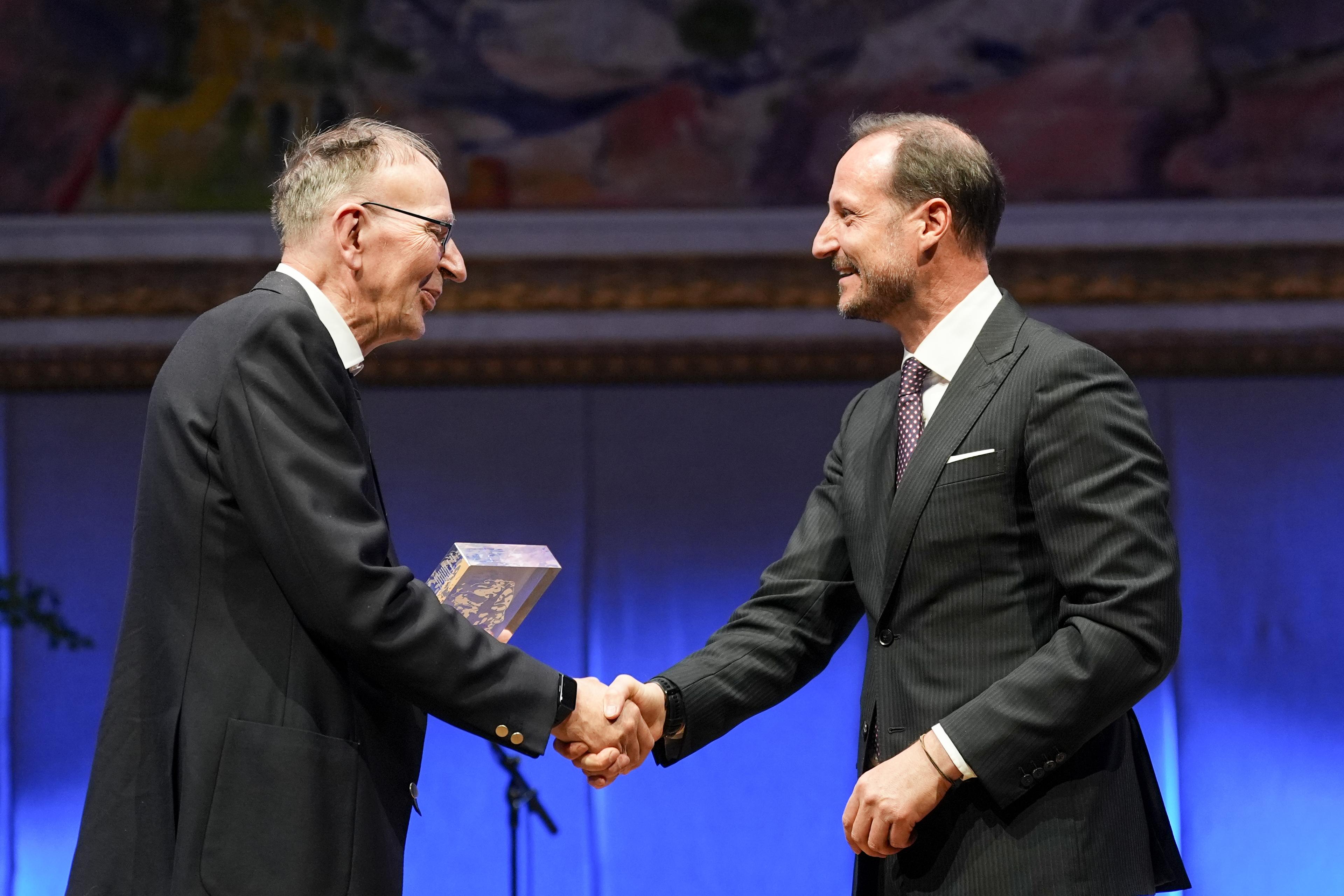 En smilende kronprins gratulerer vinneren på scenen.
