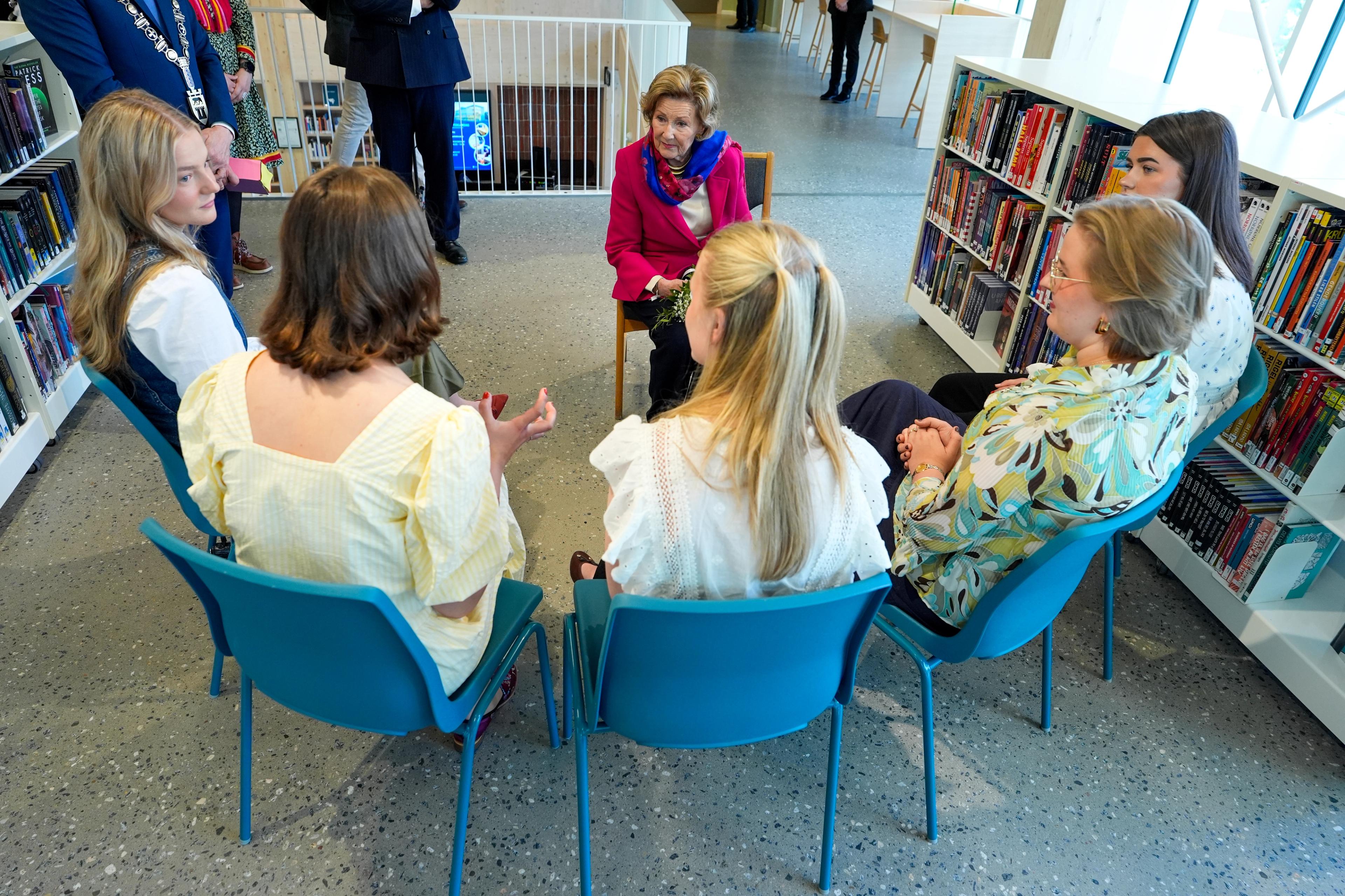 Dronning Sonja og ungdomane sit i ein ring.