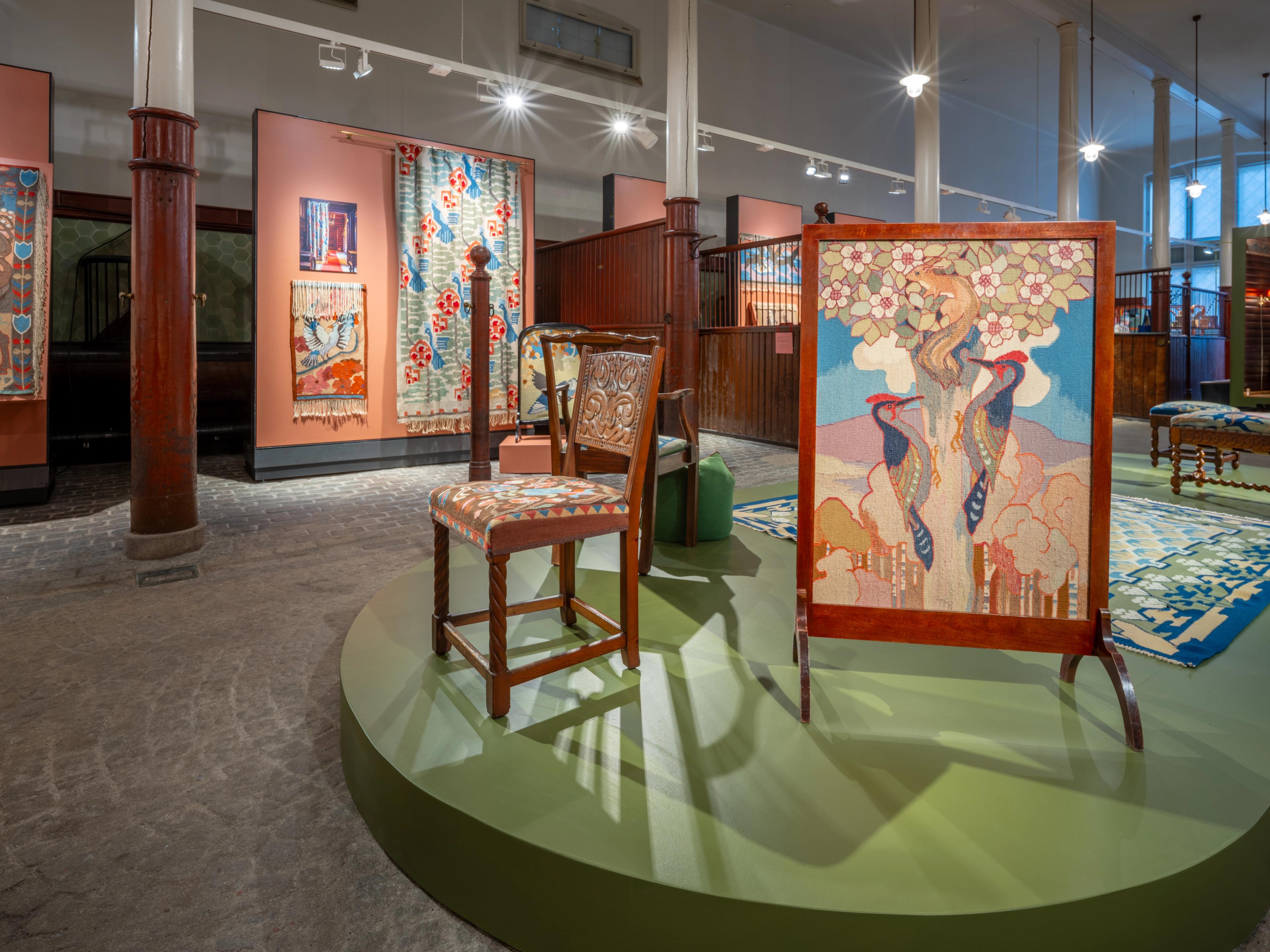 Oversiktsbilde fra KunstStallen. Stol med vevet trekk og et skjermbrett i forgrunnen.