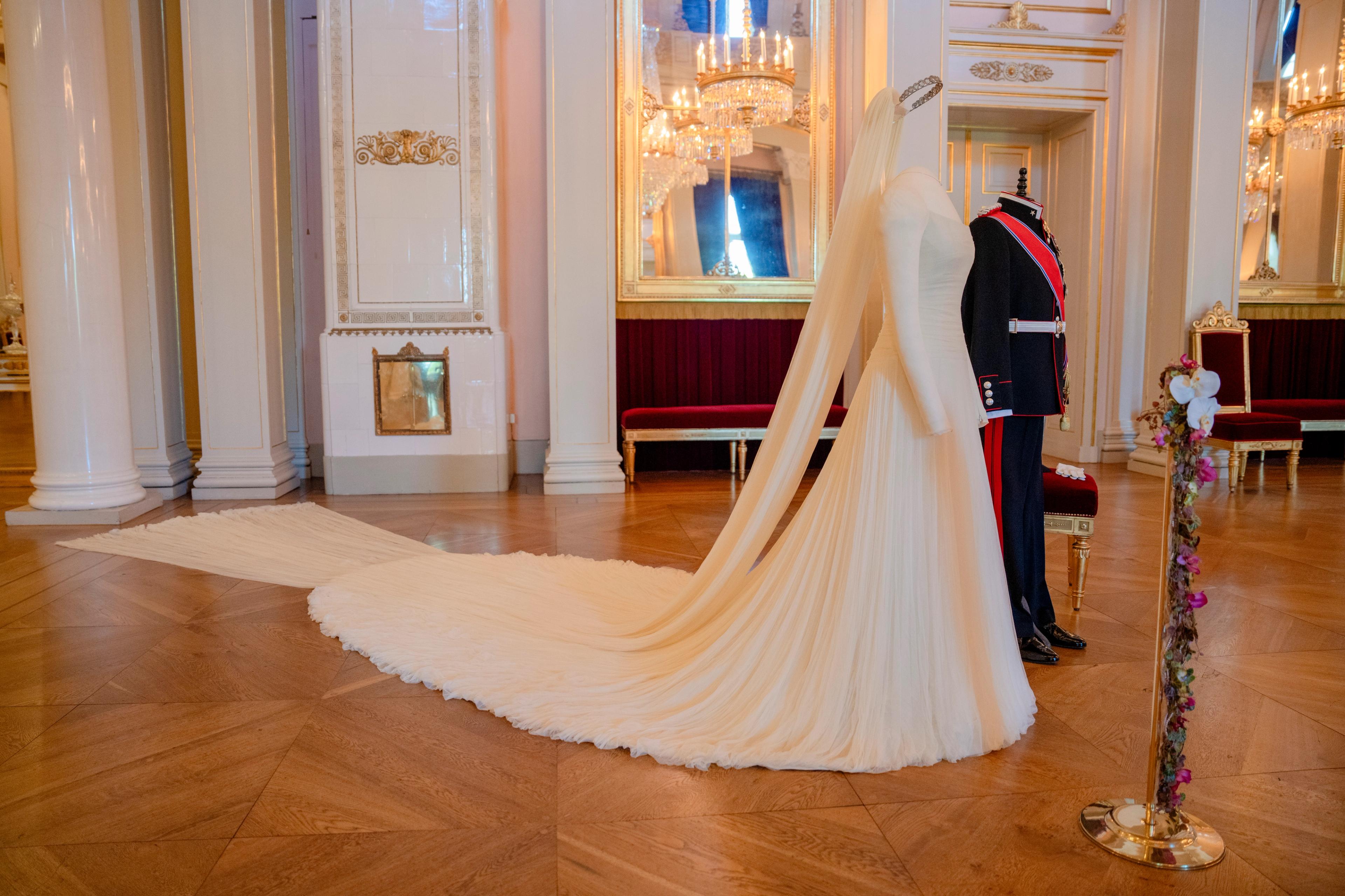 To utstillingdukker står oppstilt med henholdsvis Kronprinsens gallauniform og Kronprinsessens brudekjole med langt slørt og slep.