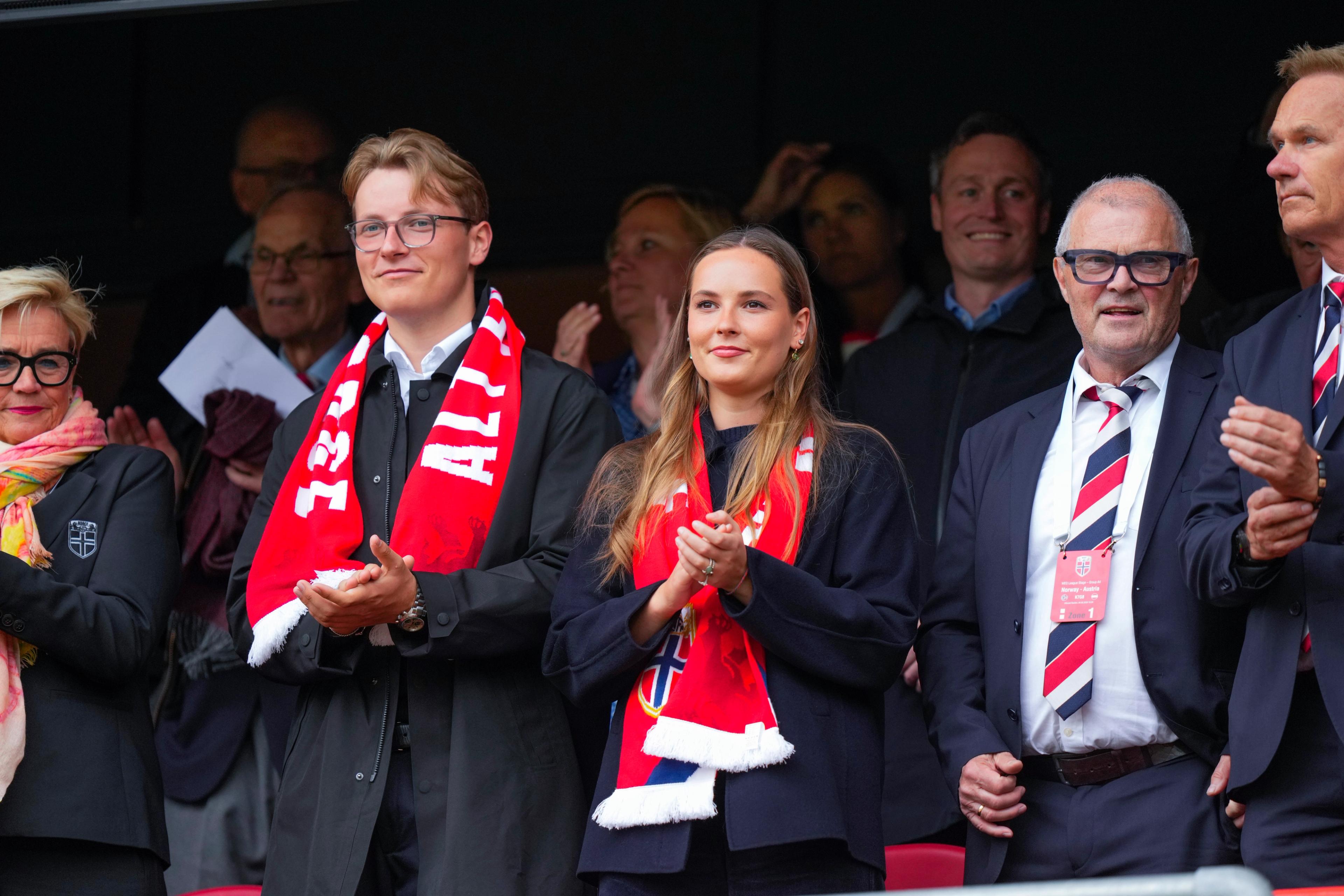 Prinsesse Ingrid Alexandra og Prins Sverre Magnus står på tribunen ikledd norske supporterskjerf.