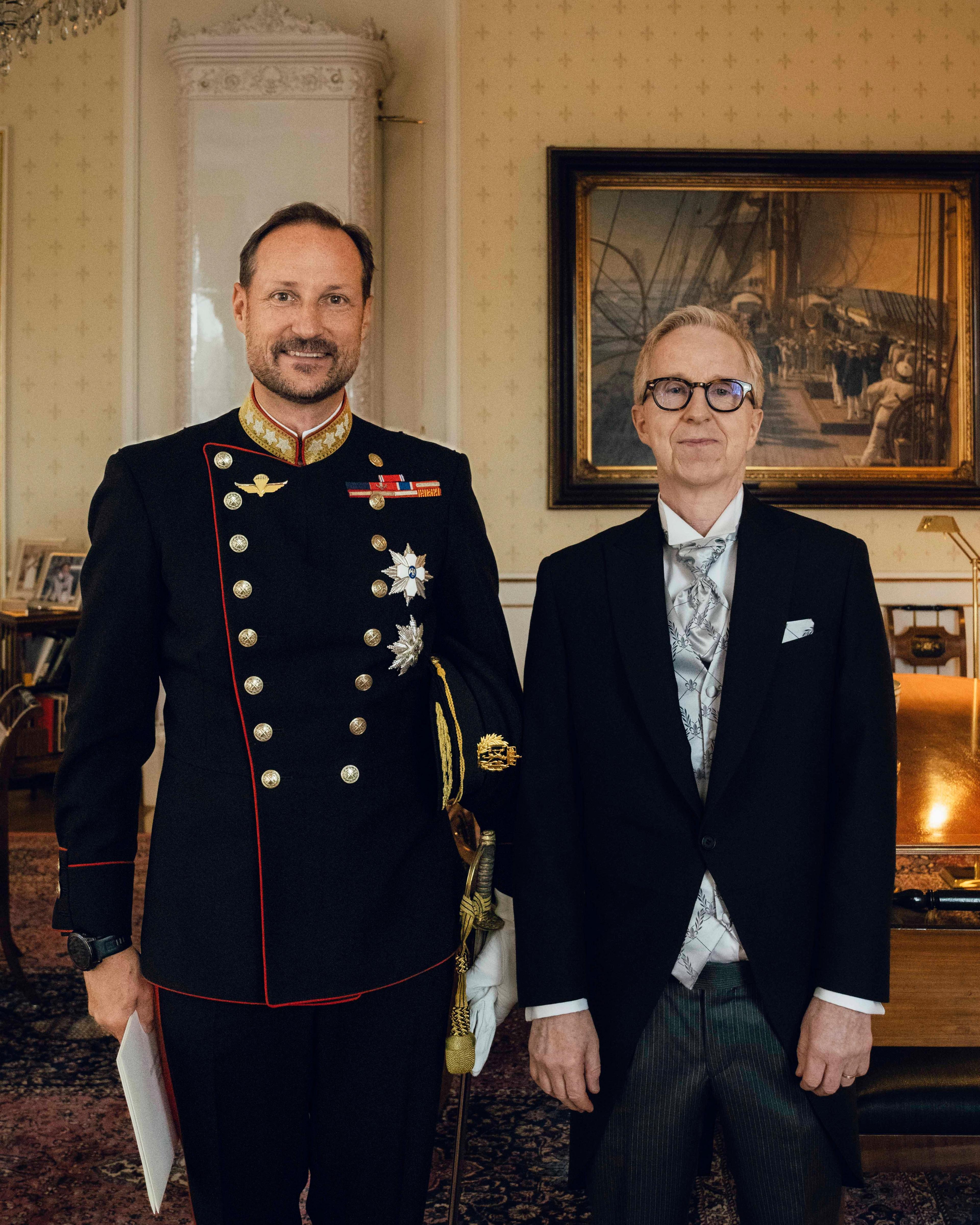 Kongen i gallauniform og ambassadøren i sjakett, står smilende ved siden av hverandre på Kongens kontor.