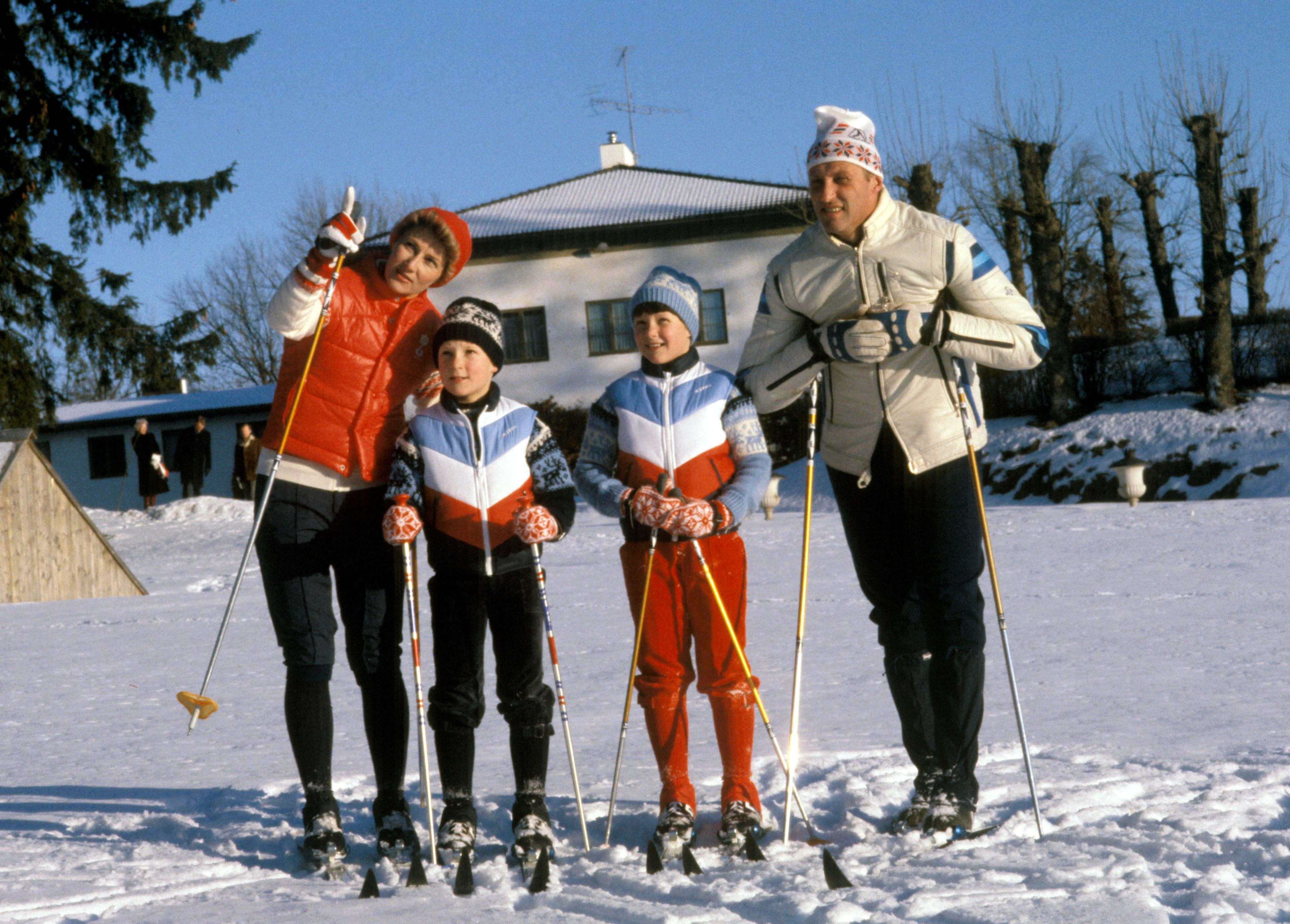 Kronprins Sonja, Prins Haakon, Prinsesse Märtha Louise og Kronprins Harald står oppstilt med ski og varme klær ute i hagen.
