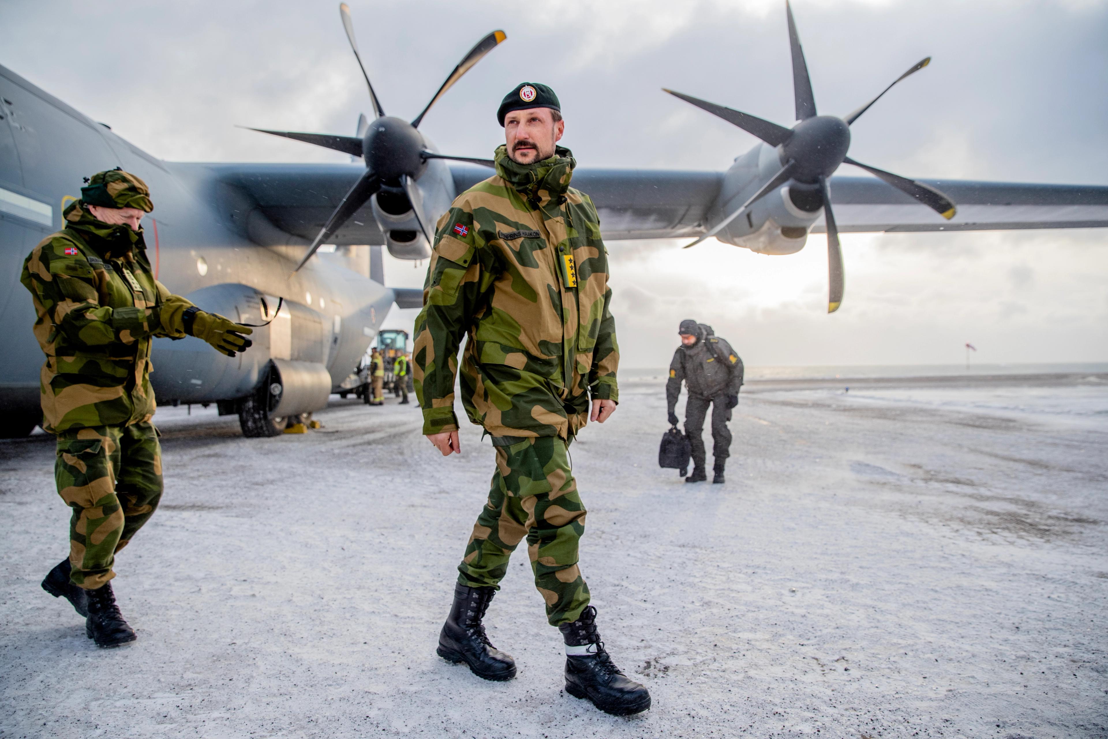 Kronprins Haakon og forsvarssjef Haakon Bruun-Hanssen går ut av forsvarets Lockheed C-130 Hercules på flyplassen.