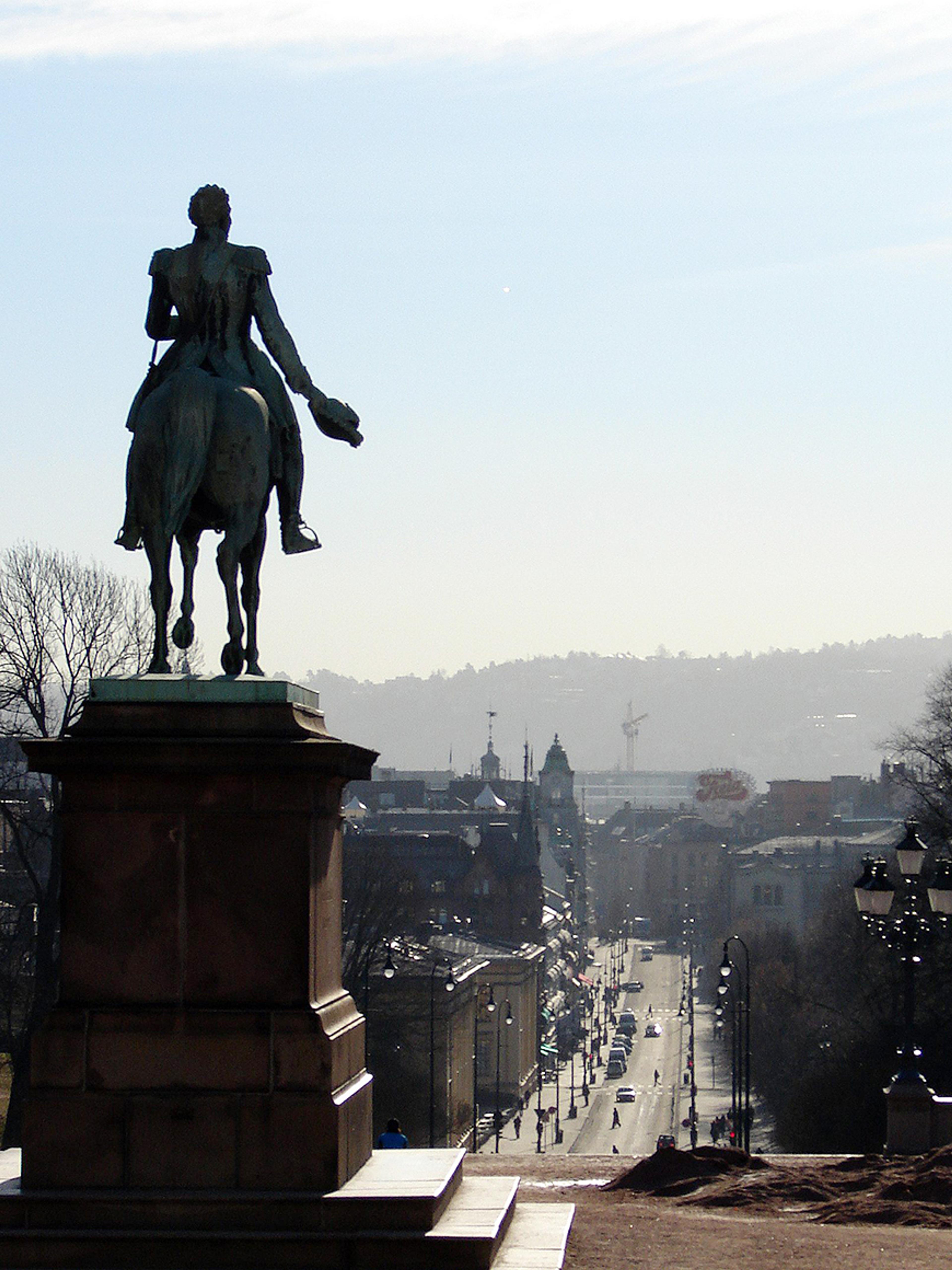 Vi ser statuen av Carl Johan bakfra, og dermed ligger byen foran ham.