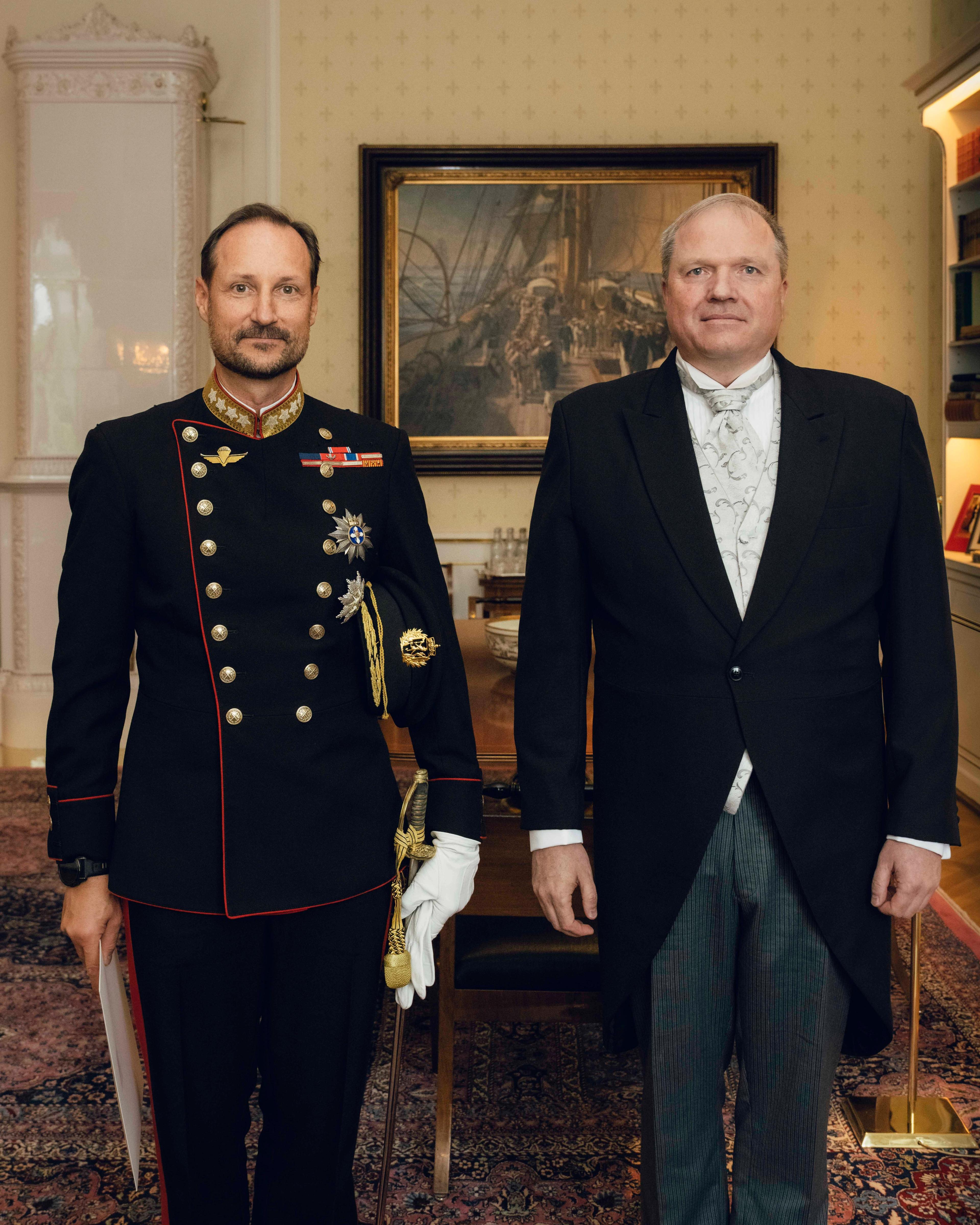Kongen i gallauniform og ambassadøren i sjakett står smilende ved siden av hverandre på Kongens kontor.