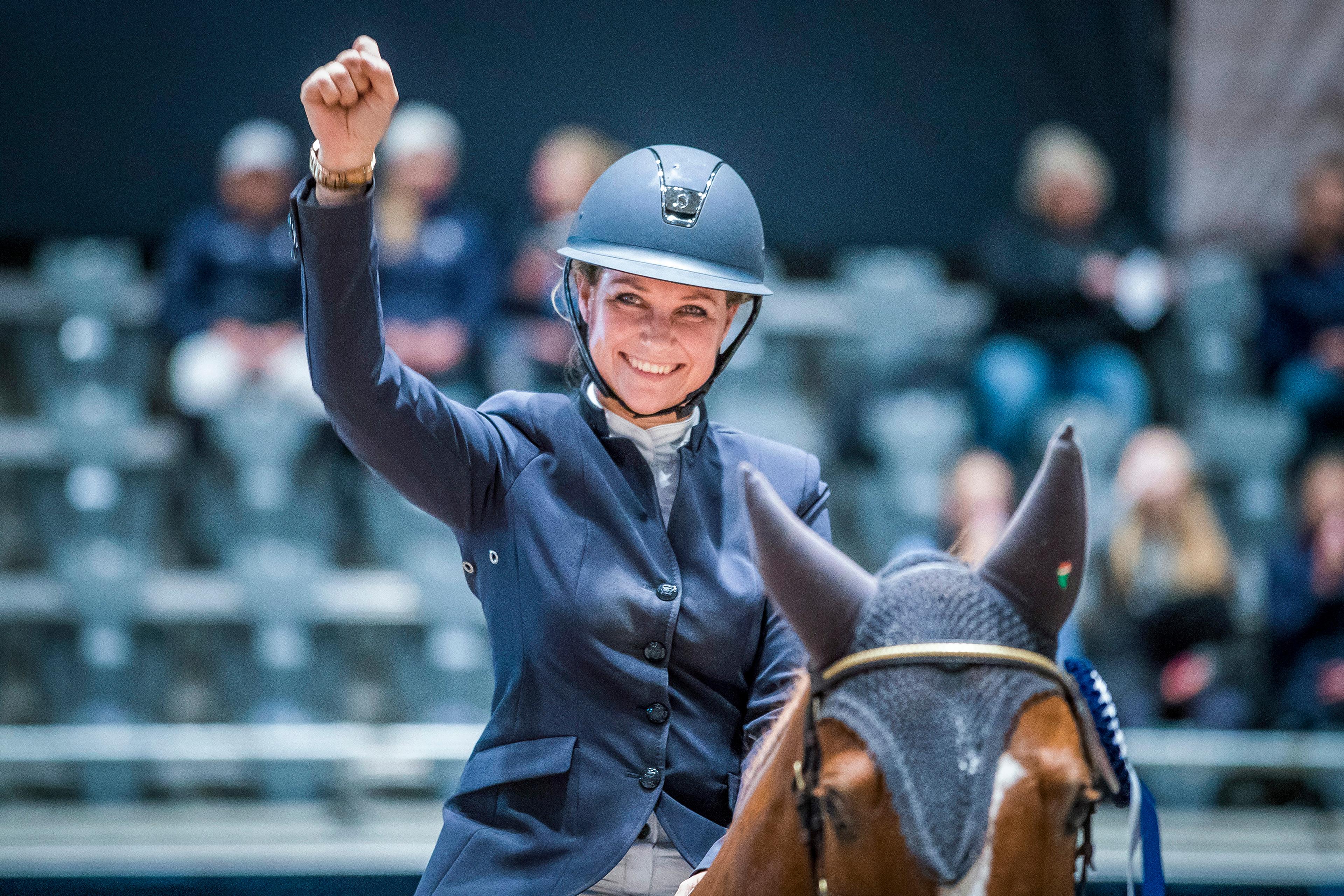 Prinsessen sitter smilende til hest iført ridejakke og hjelm.