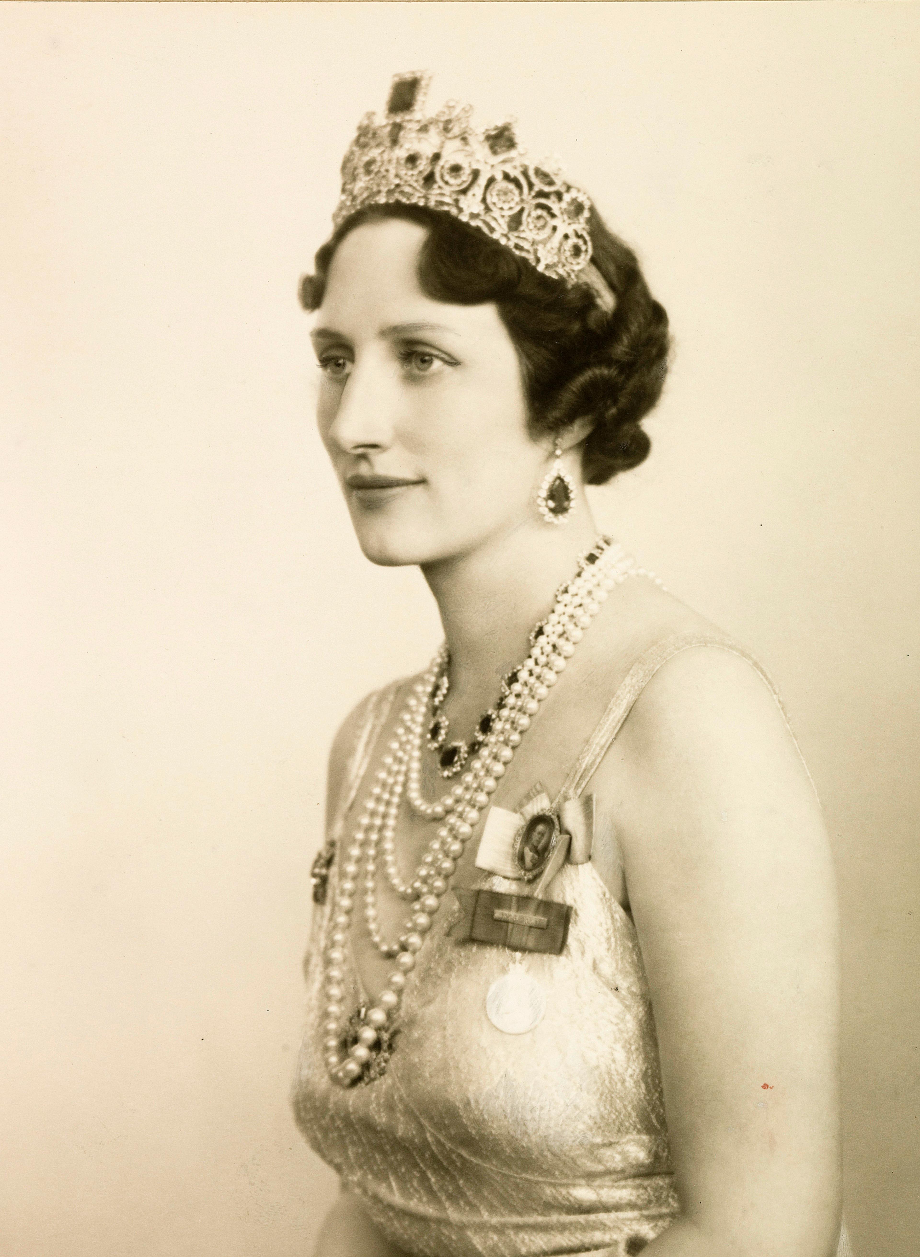 Portrett av Kronprinsesse Märtha i lys, ermeløs kjole, perlekjeder og tiara.