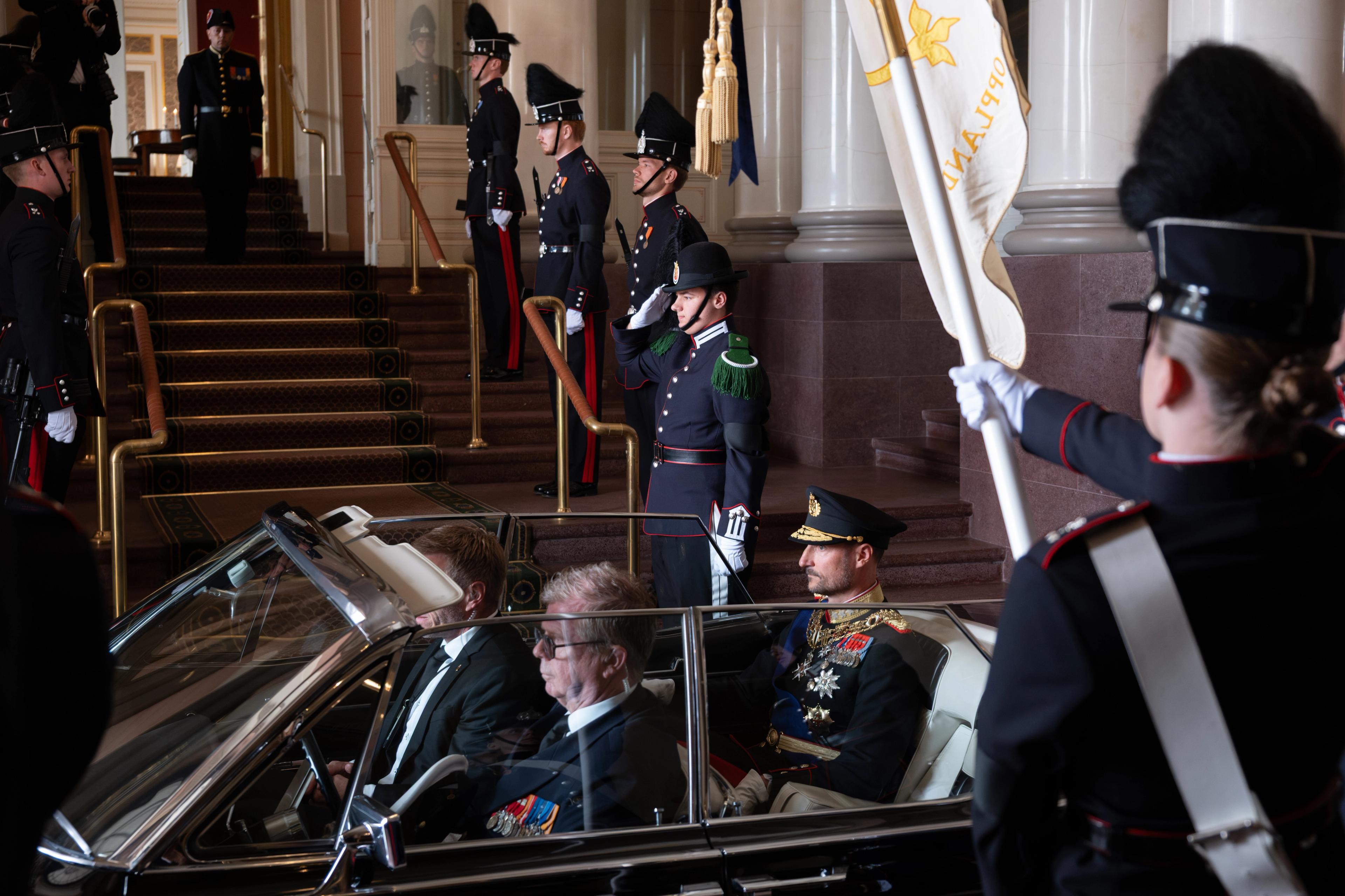 Kong Haakon sitter i bilen A-5 med kadetter stilt opp på hver side