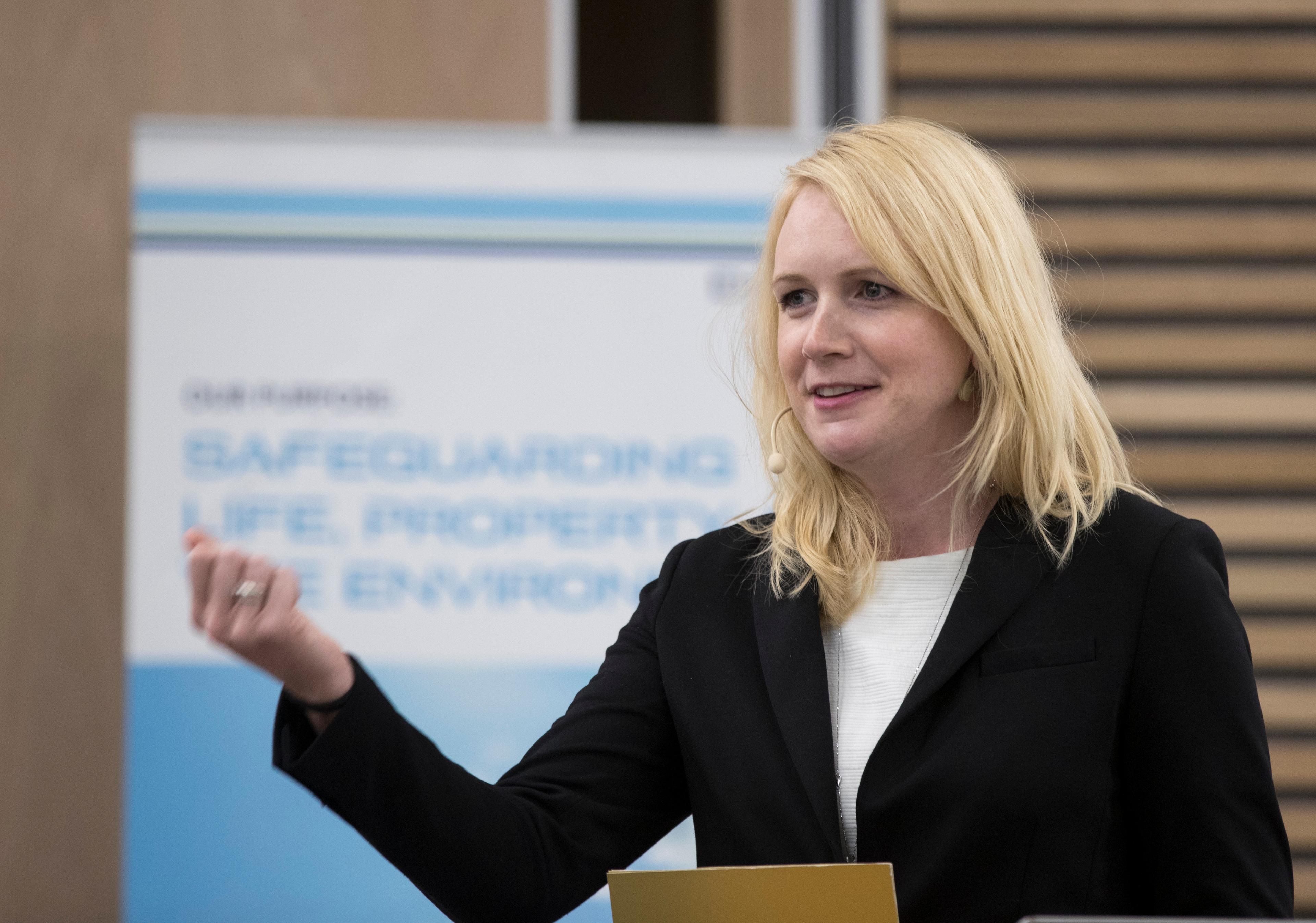Lystrup snakker foran en skjerm med bilde av rapportens forside.