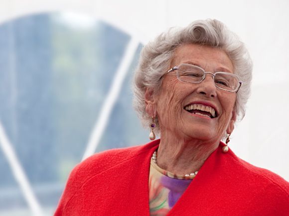 Prinsesse Astrid i rød jakke, ler høyt.