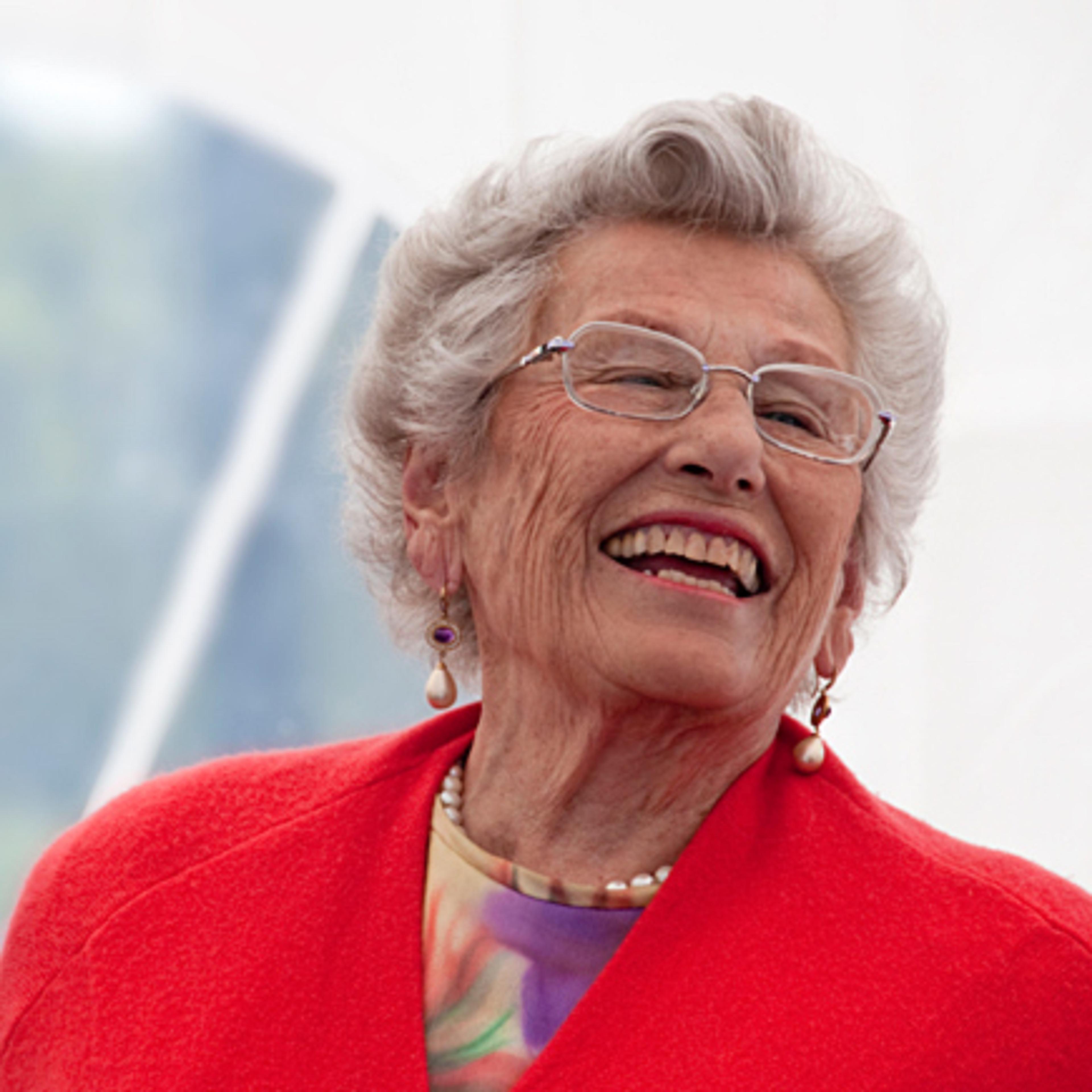 Prinsesse Astrid i rød jakke, ler høyt.