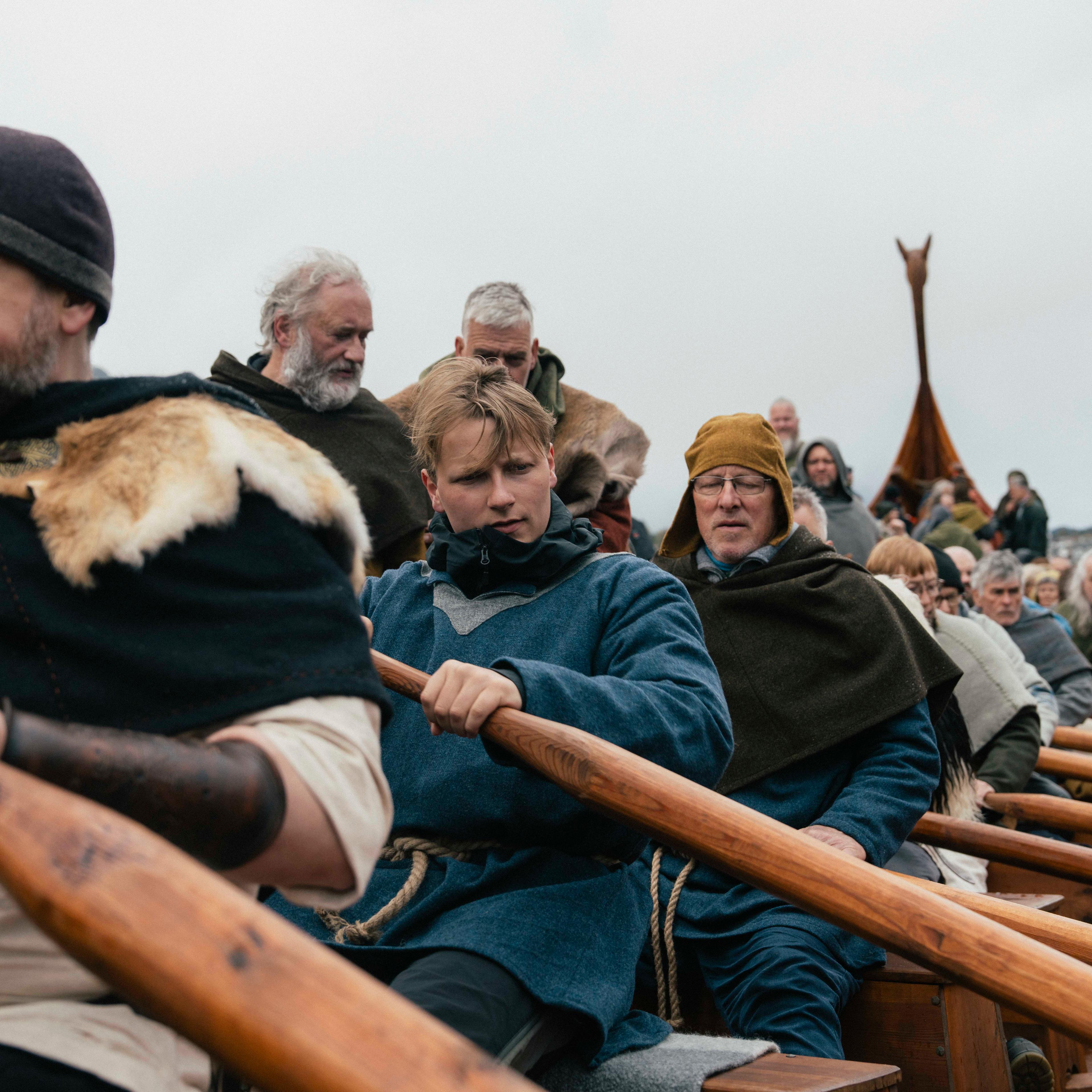 Prins Sverre Magnus om bord i et vikingskip, med åre i hånda. Han sitter på en rekke med folk som er kledd vikingantrekk