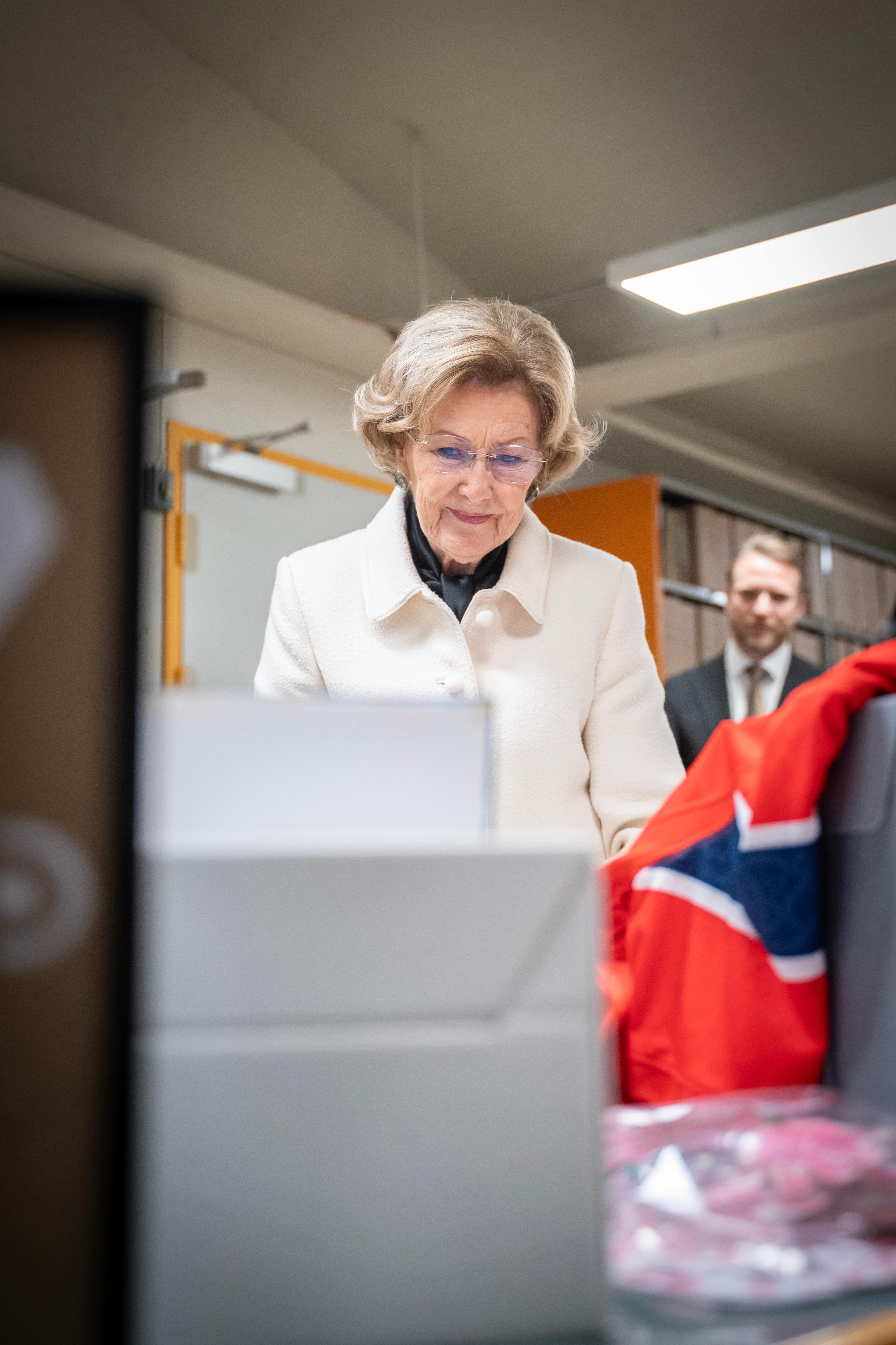Dronning Sonja smiler lurt mens hun ser på tegningene og hilsenene som ligger fremme.
