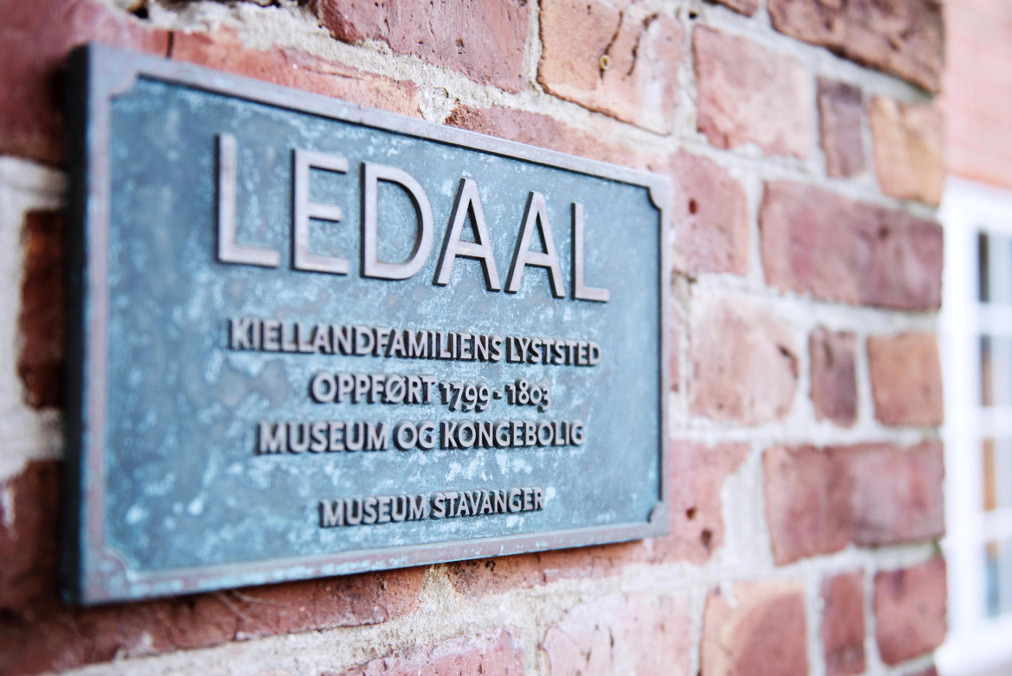 Et skilt på en murvegg gir opplysninger om stedet.