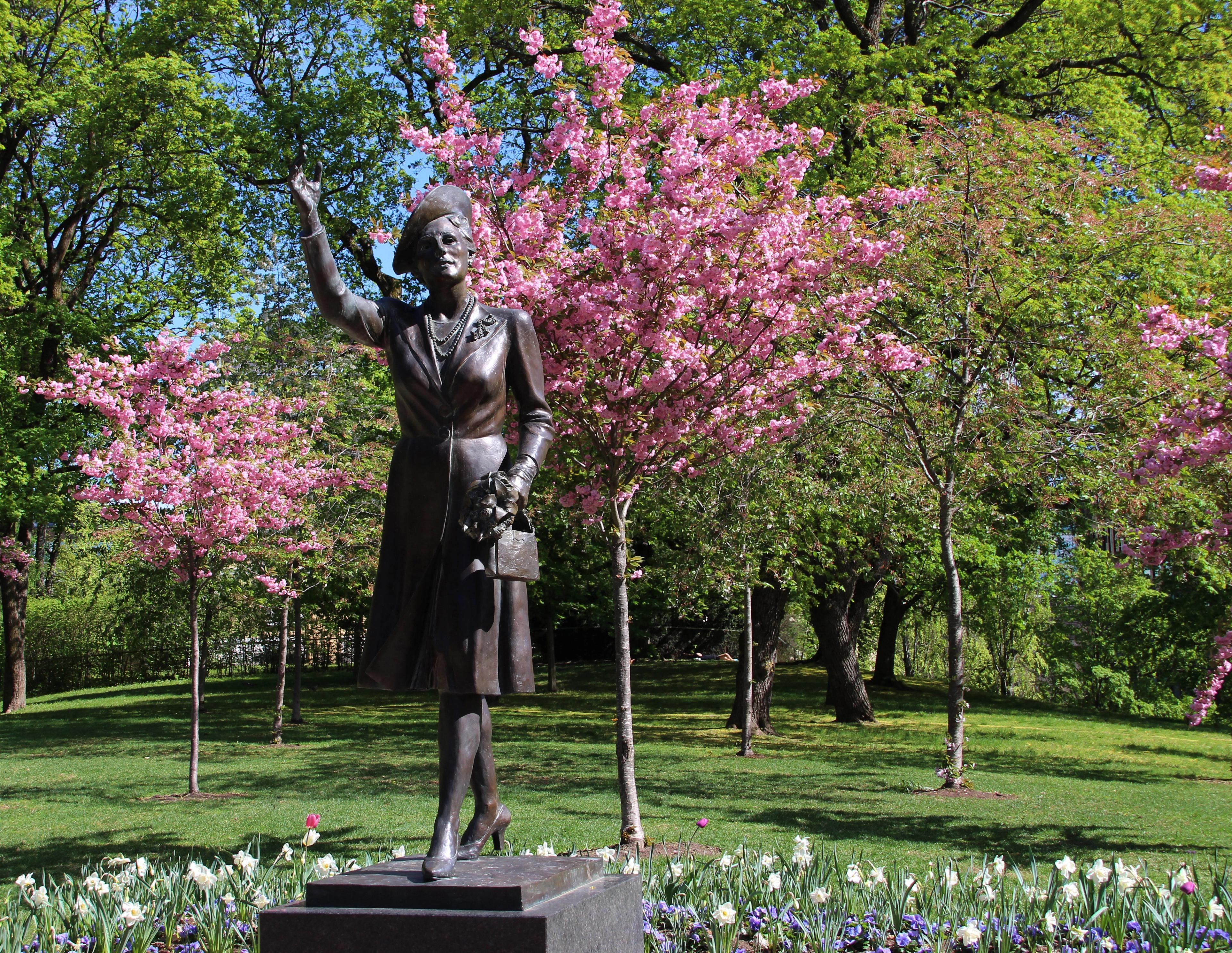 En rekke trær fulle av blomster i ulike rosafarger står bak statuen av Kronprinsessen.