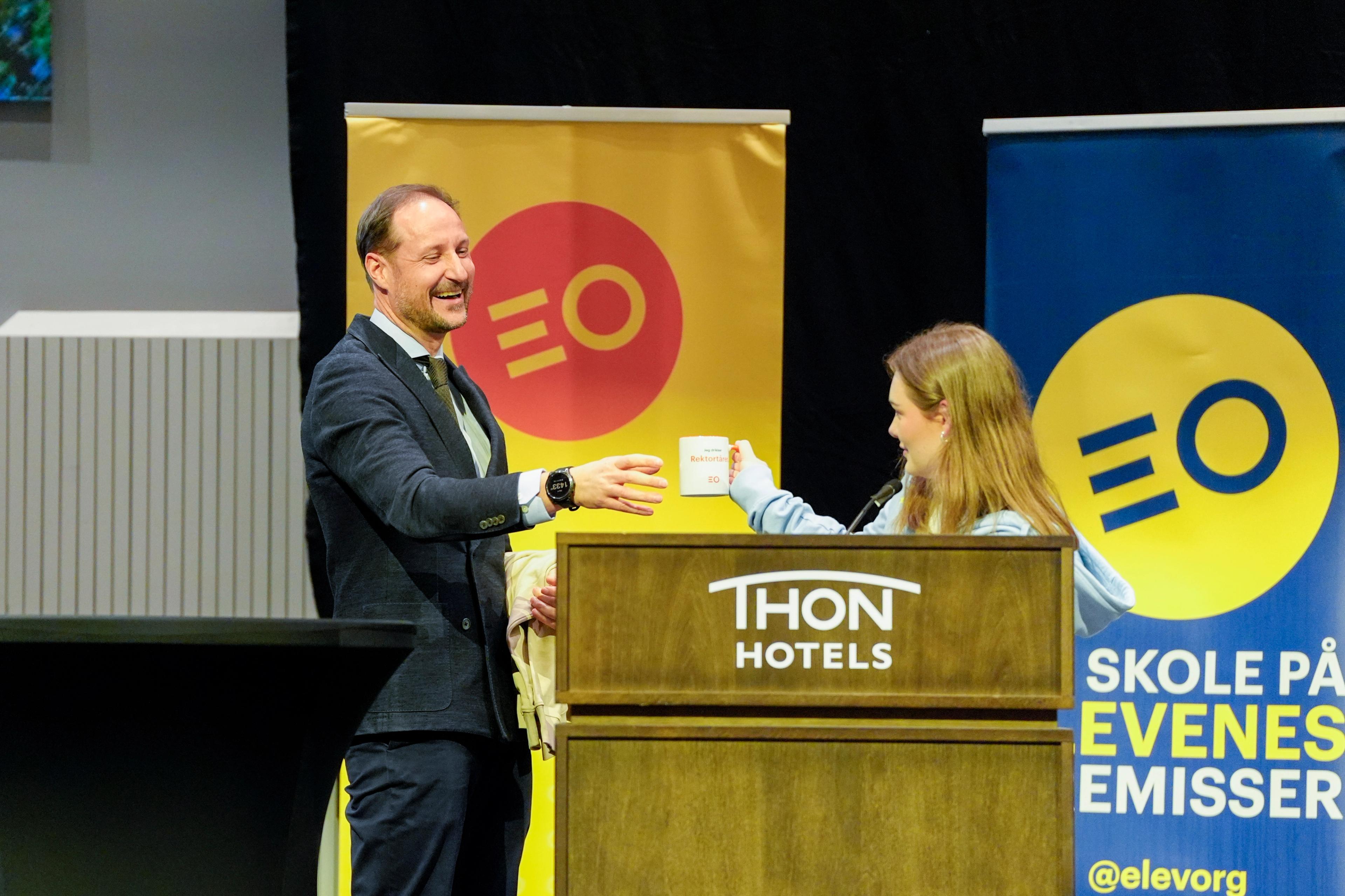 Kronprins Haakon ler medan han tek imot ein kopp med påskrifta «Eg drikk rektortårer».