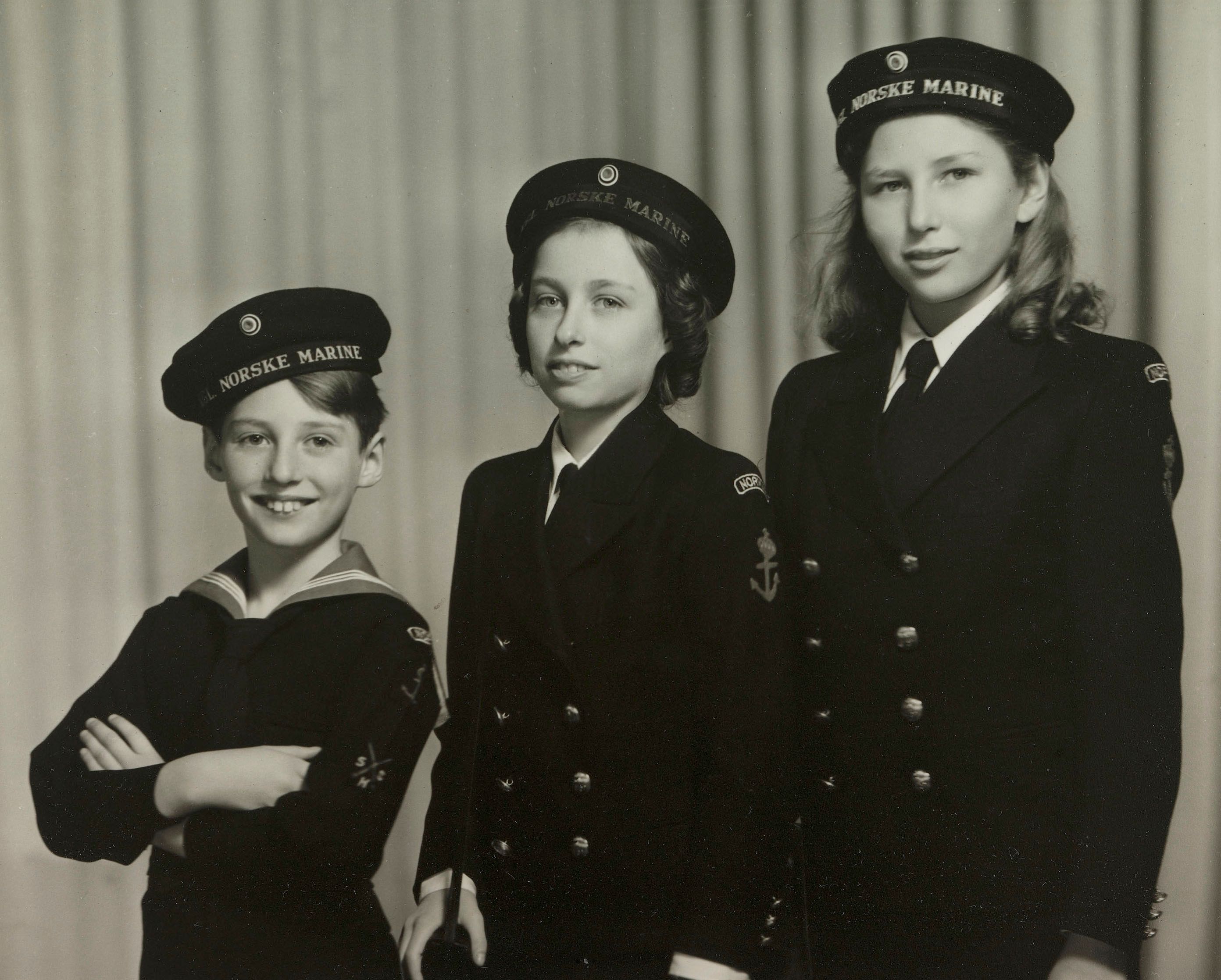 De tre barna står på rekke i uniformer som fra den norske marinen.