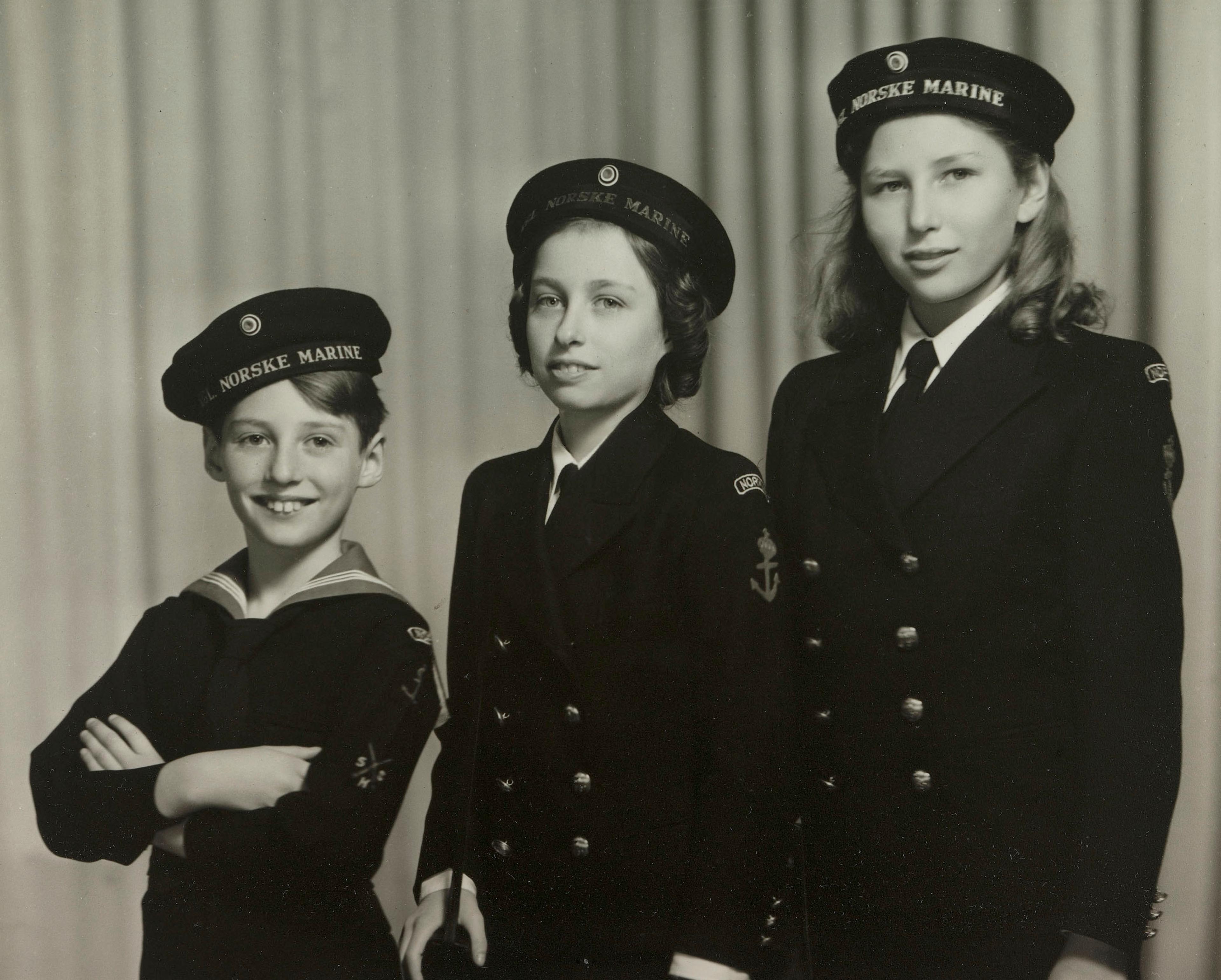 De tre barna står på rekke i uniformer som fra den norske marinen.