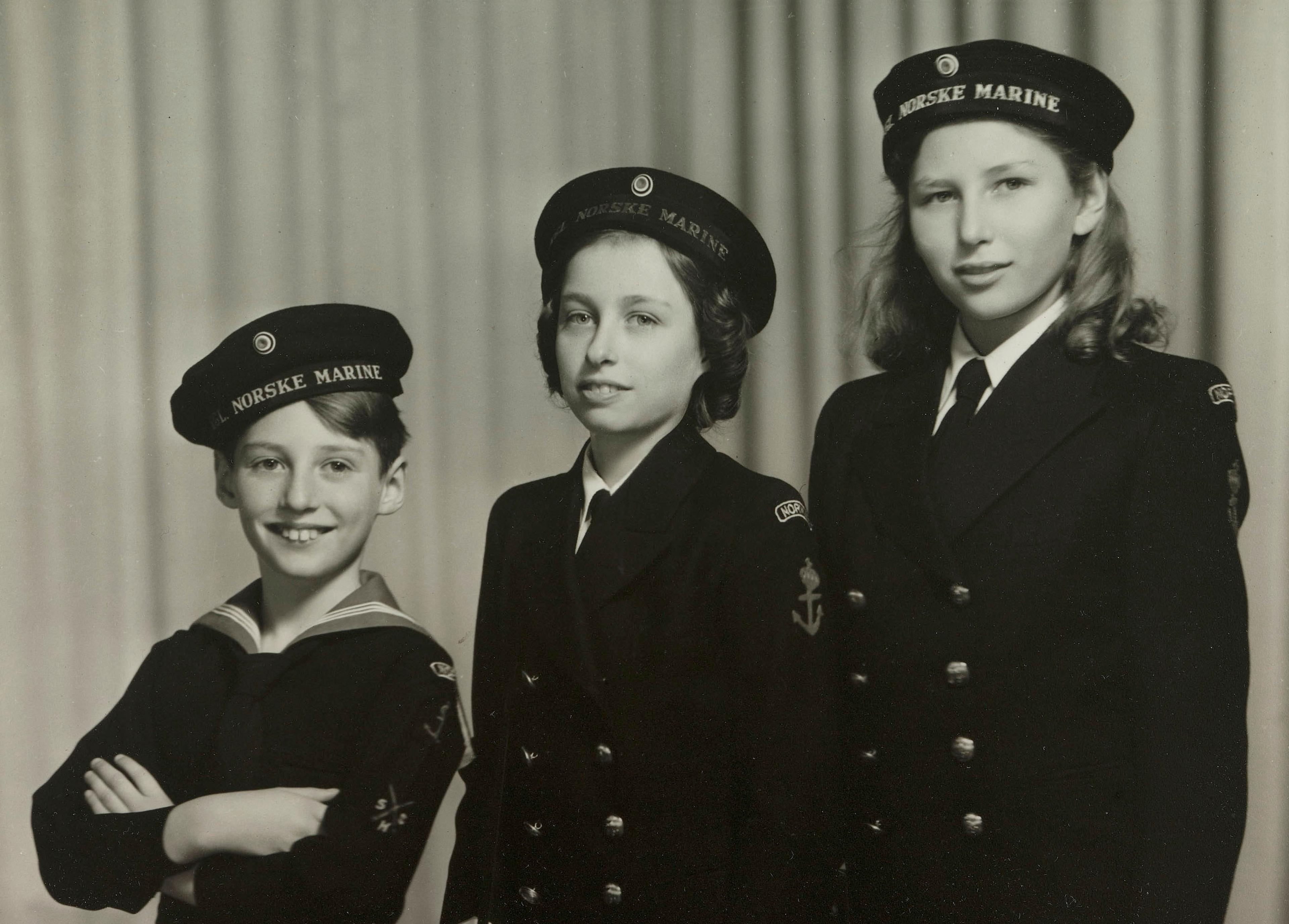 De tre barna står på rekke i uniformer som fra den norske marinen.