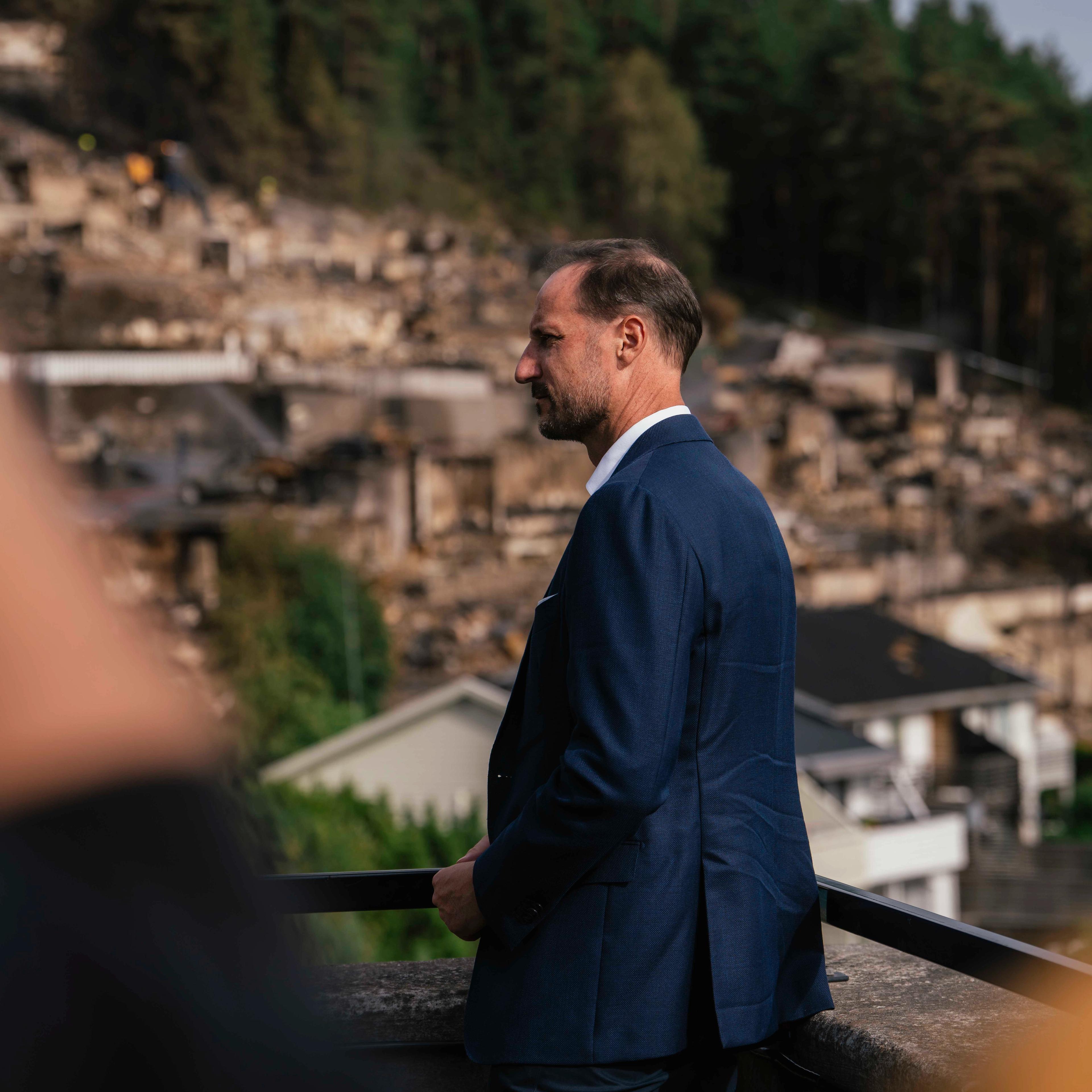 Kronprins Haakon ser på brannruinene i Krokstadelva