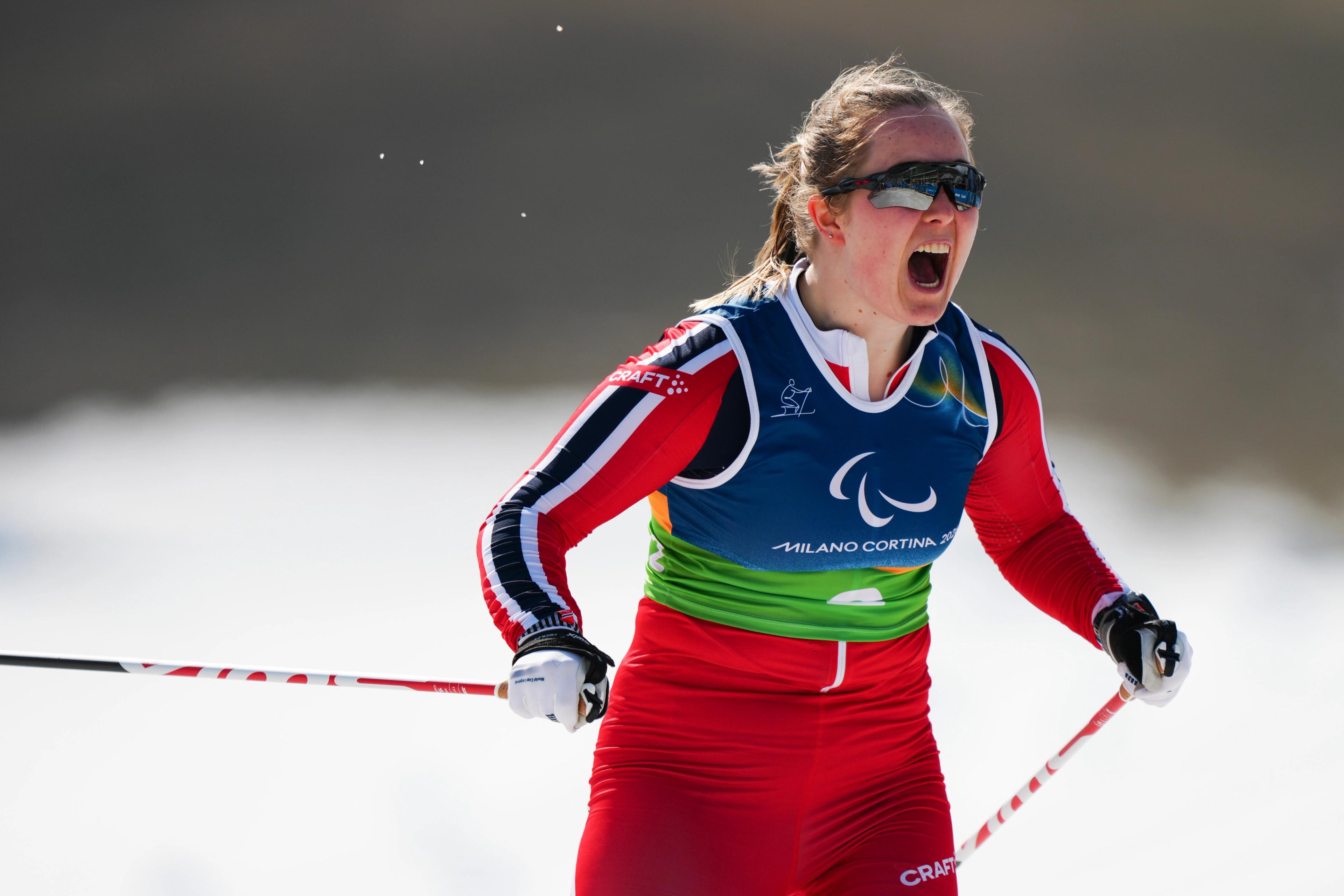 En jublende Nilsen i Norges røde drakt med blå og hvite striper på ermene og staver i hendene.