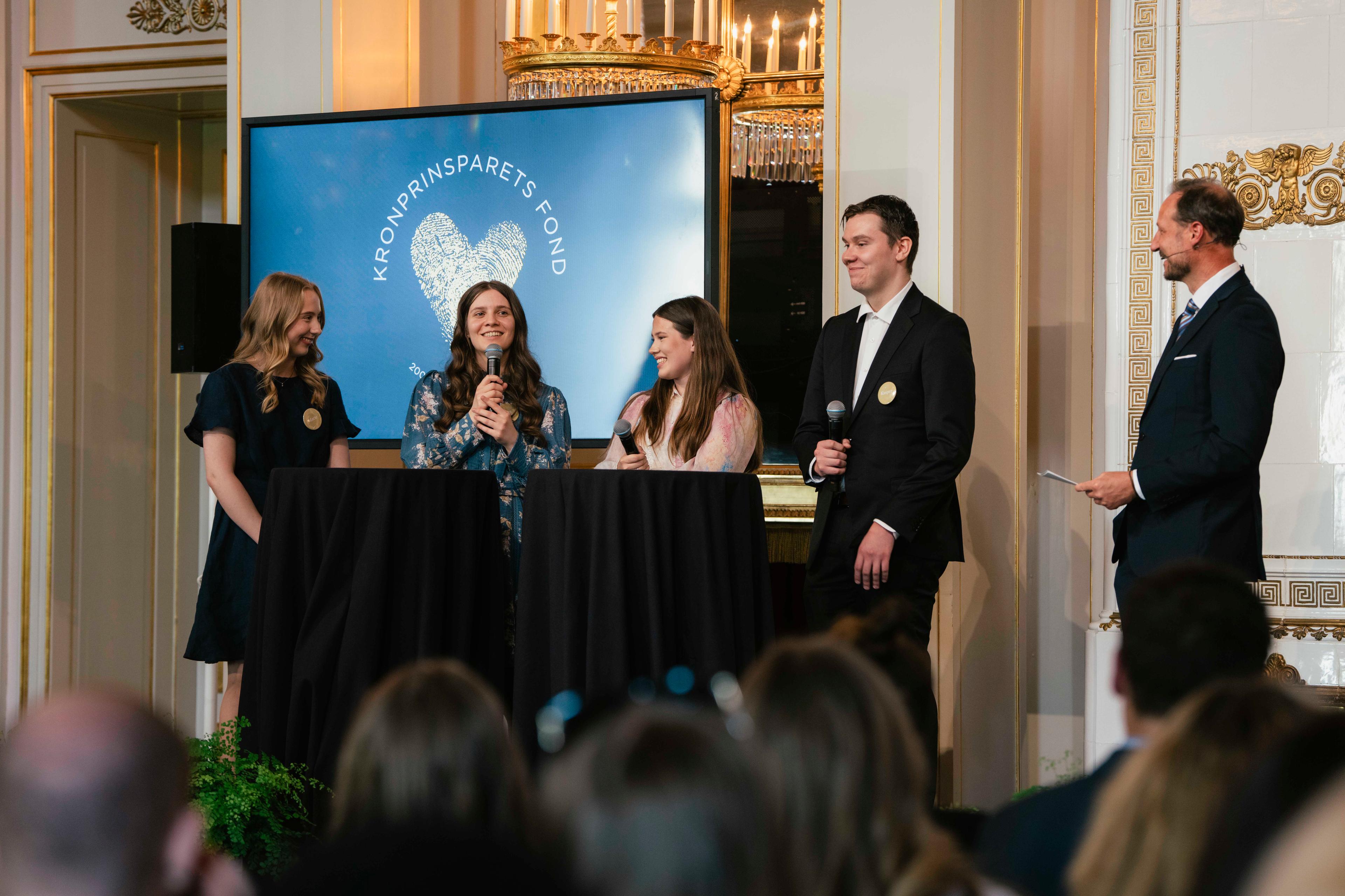 Kronprinsen og fire ungdommer med mikrofonser på scenen.
