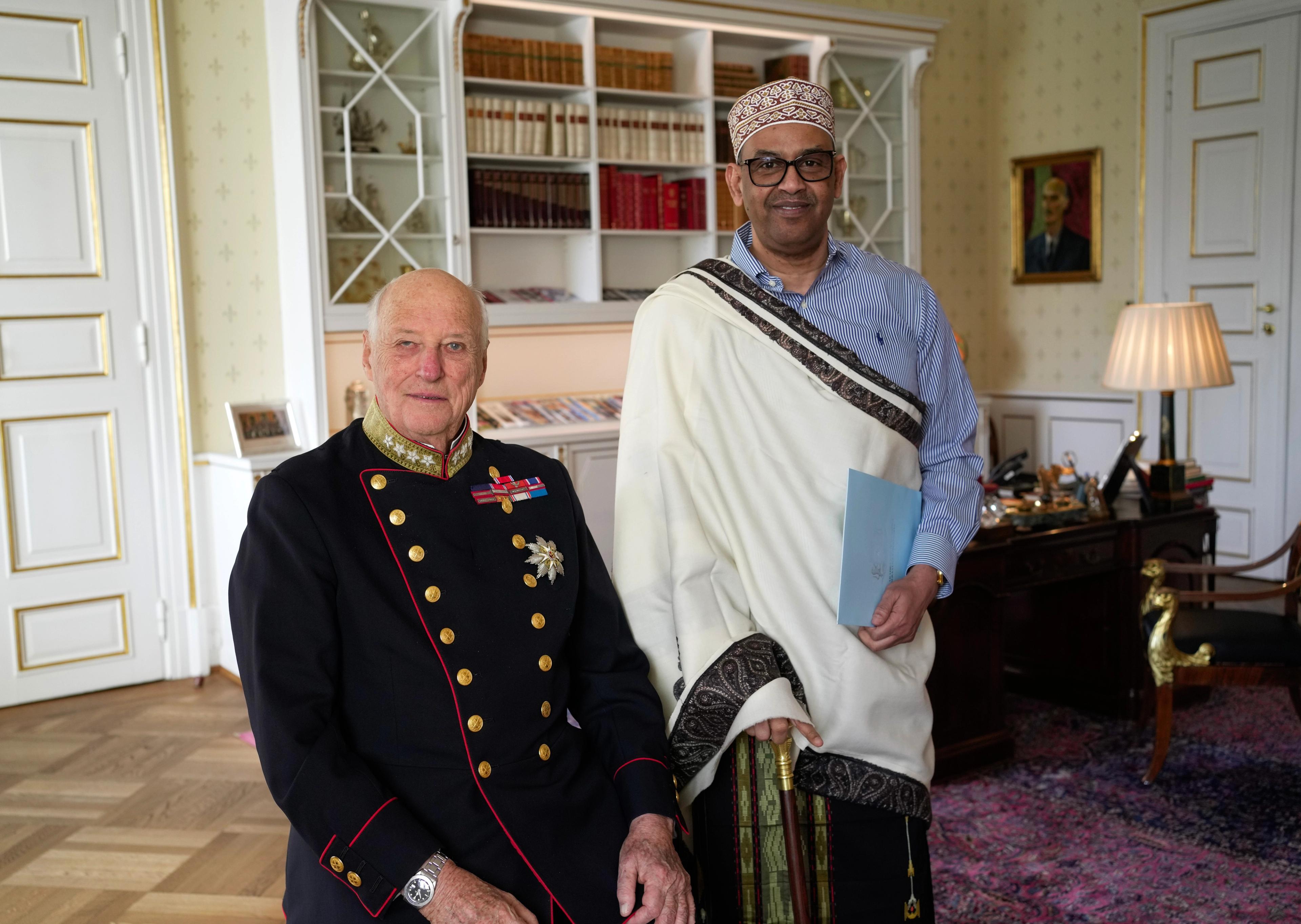 Kongen og ambassadøren smilende ved siden av hverandre på Kongens kontor.