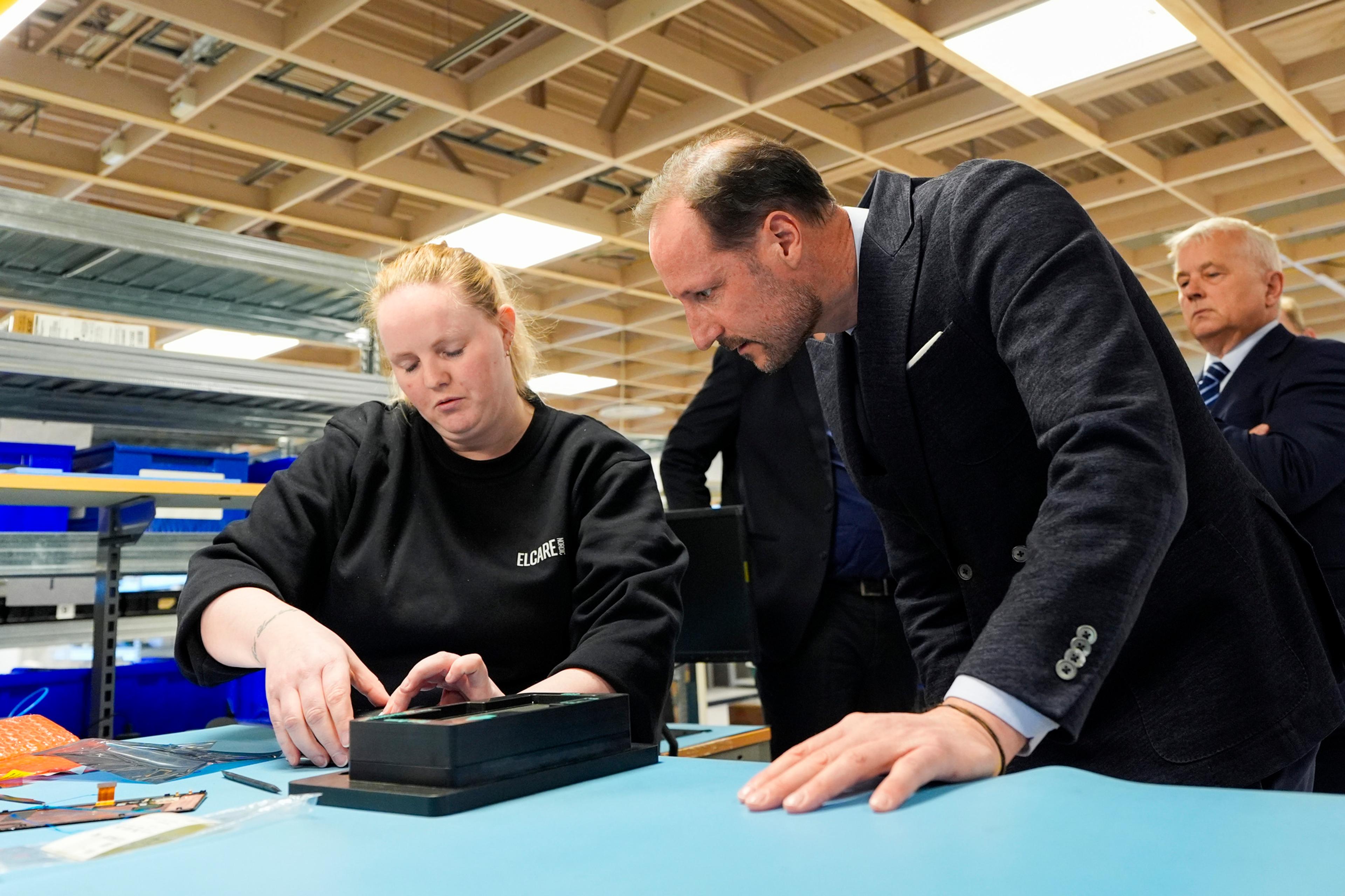 Kronprinsen sammen med medarbeider hos Elcare reparerer telefon.