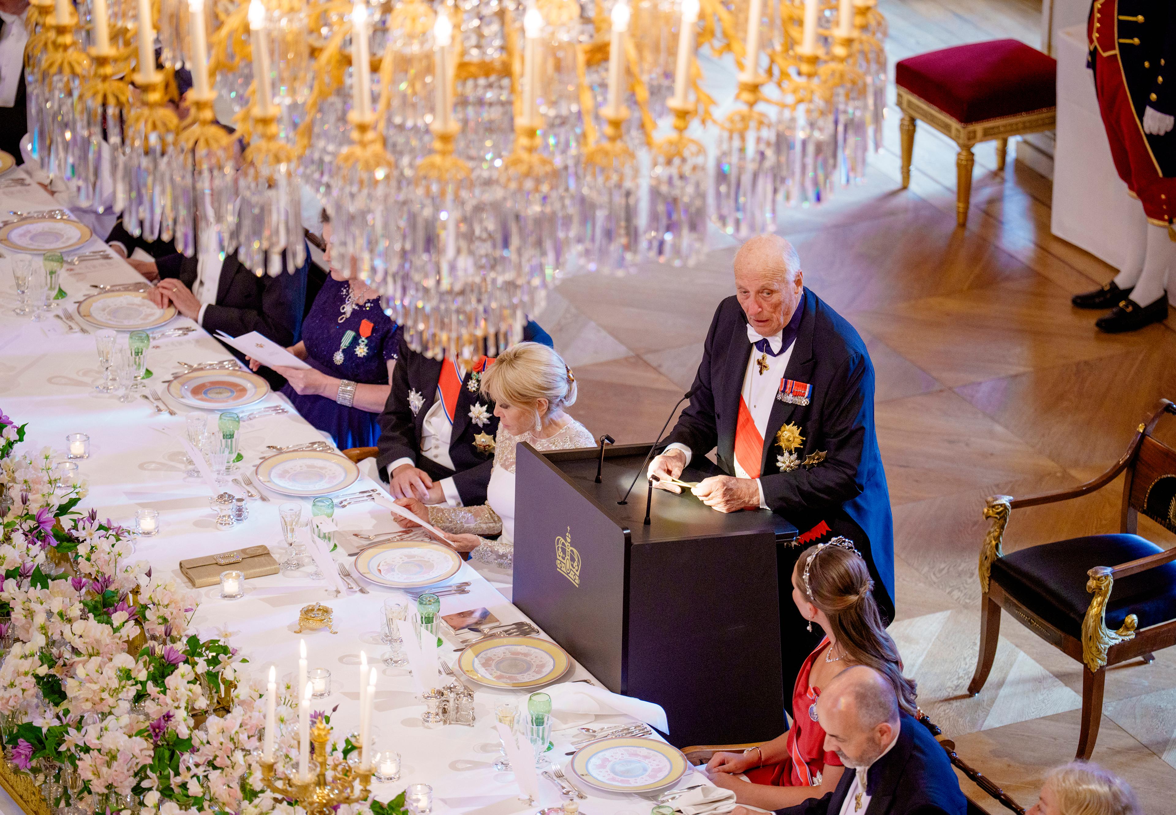 Kongen står ved en talerstol plassert ved det festdekkede bordet.