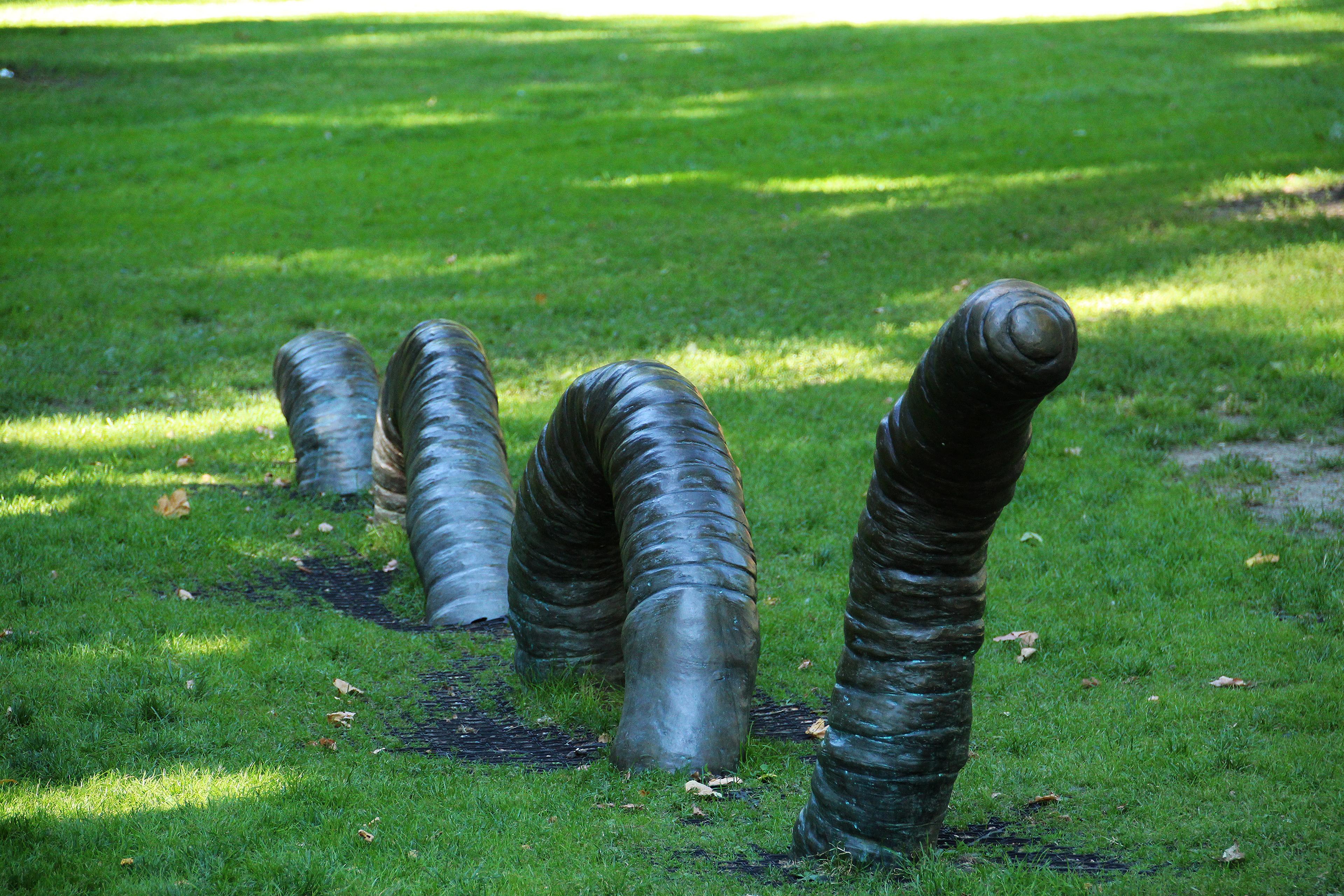 En stor mark støpt i mørkt metall bukter seg opp fra gresset.