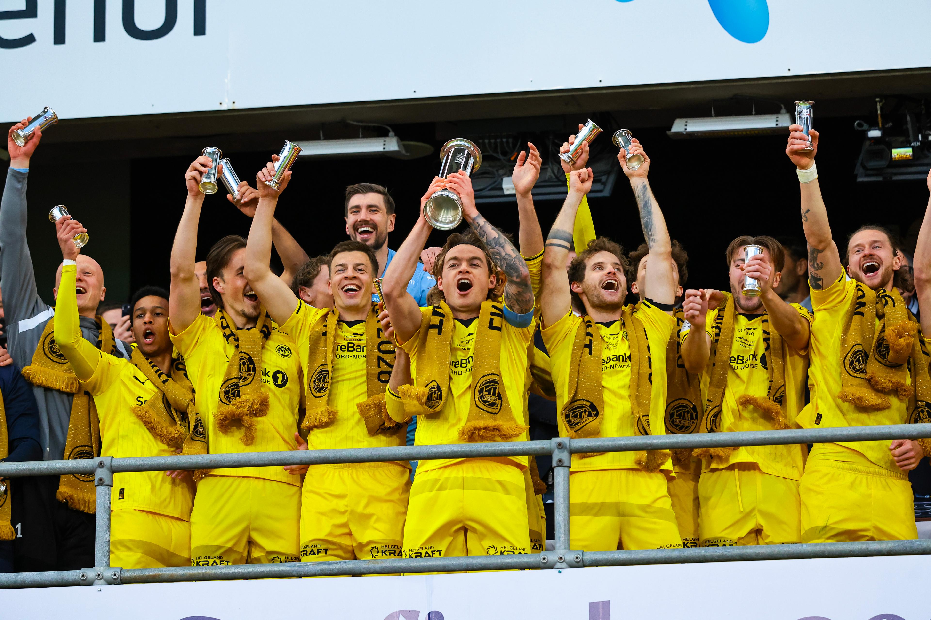 Glimt-spillerne løfter pokalene og kongepokalen foran Kongen.