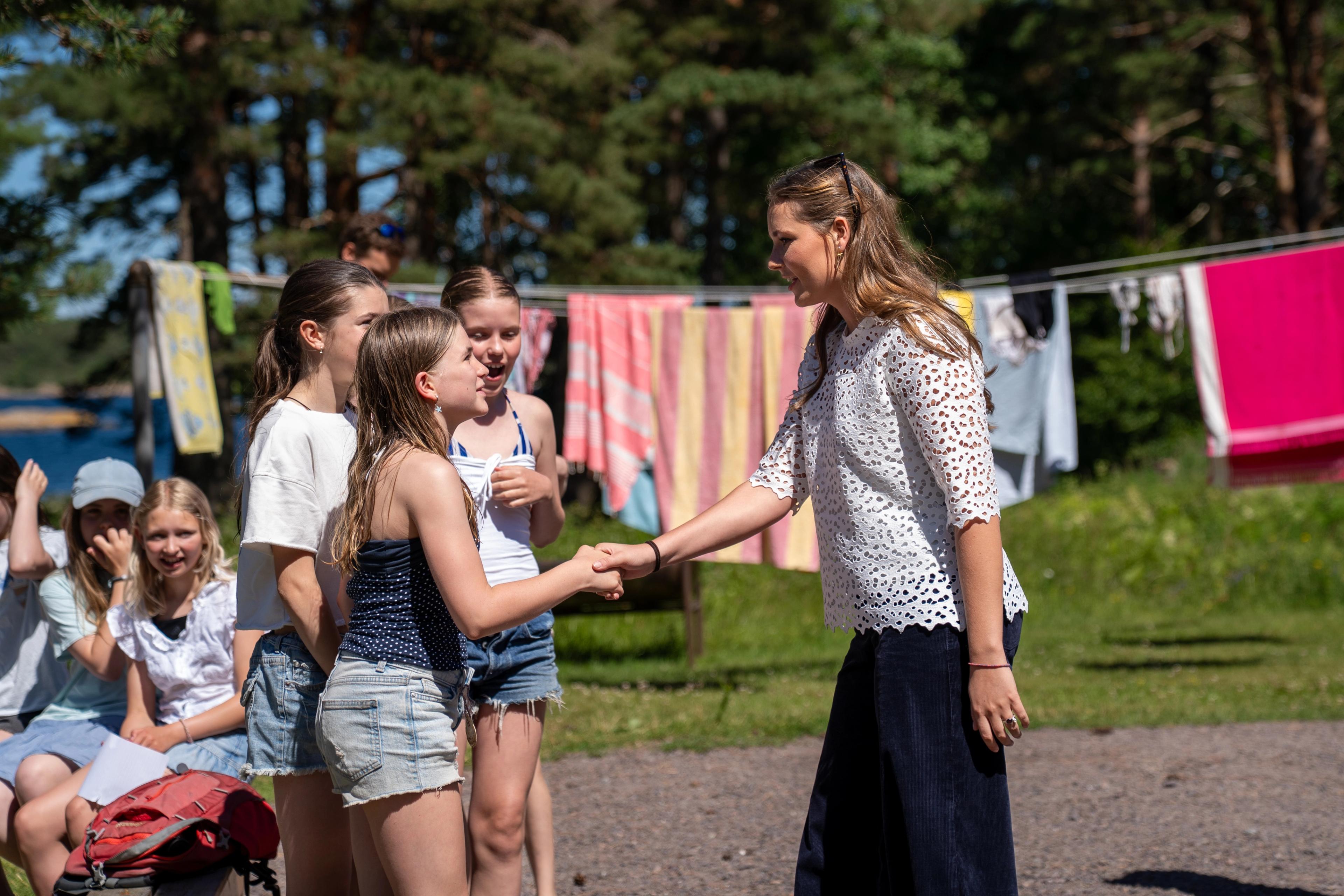 Prinsessen hilser på en av jentene. Bak skimtes fargerike håndklær på snorer.
