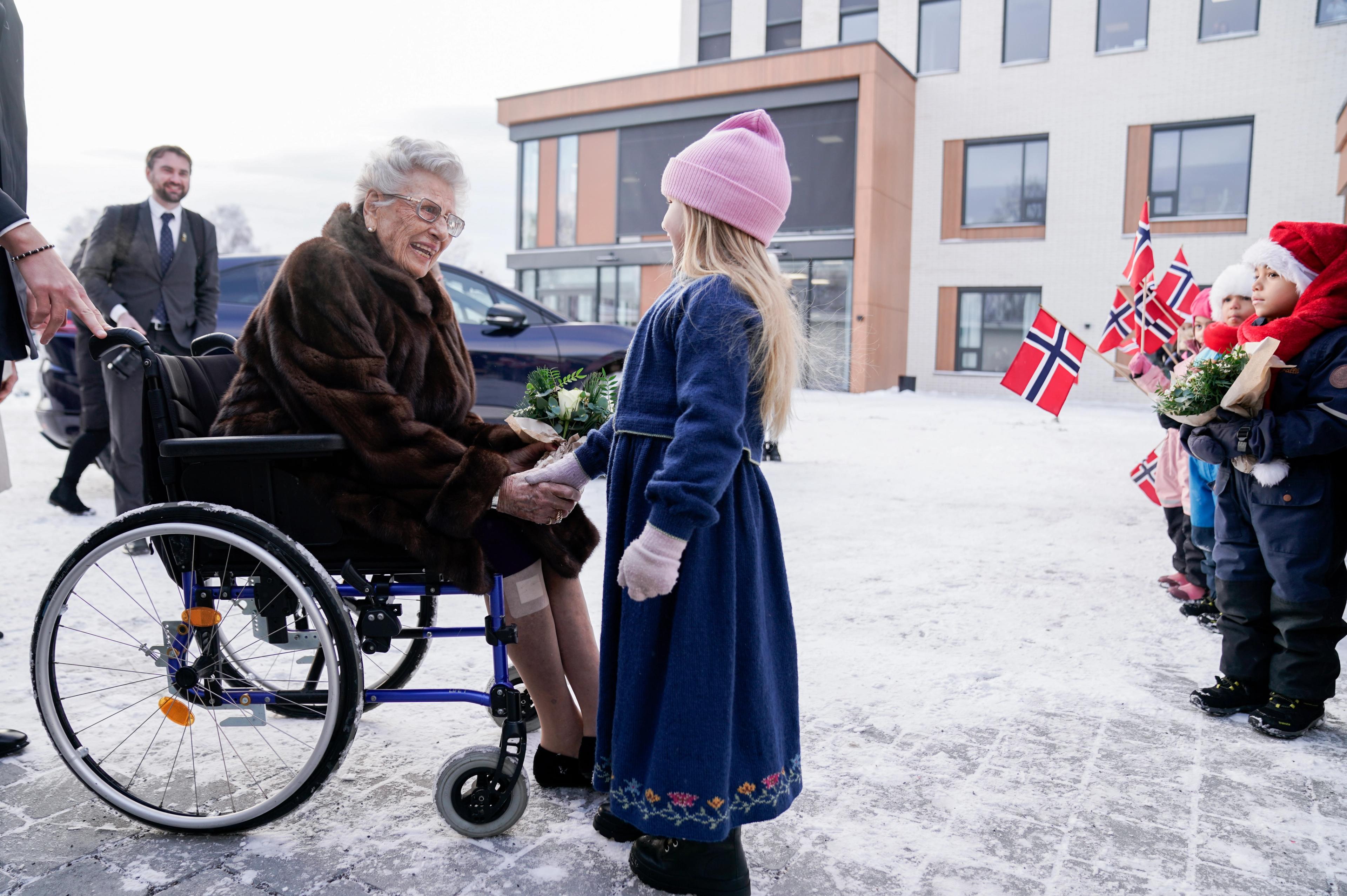 Prinsesse Astrid i rullestol snakker med en liten pike som har gitt henne blomster.