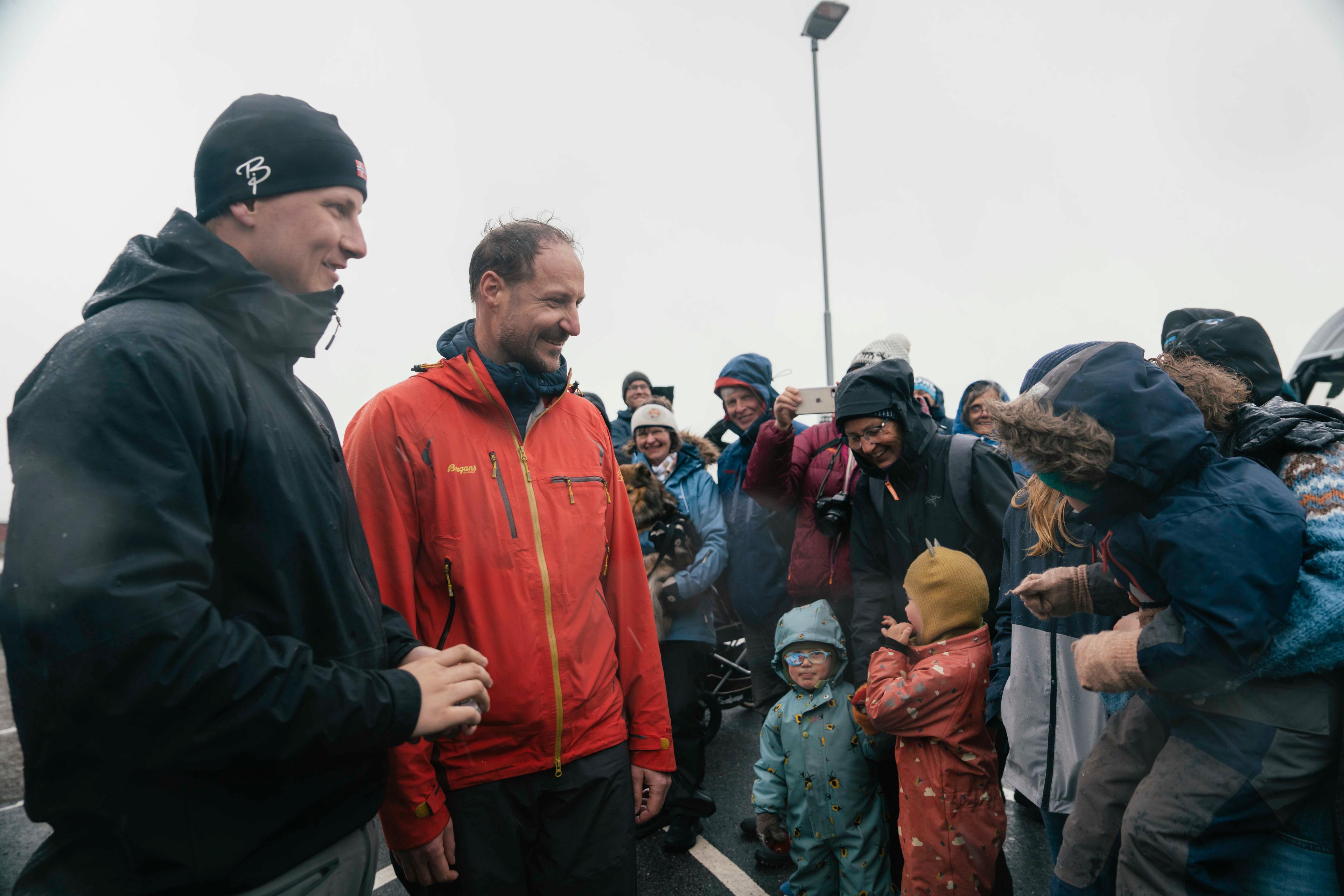 Kronprins Haakon og Prins Sverre Magnus møter ivrige barn og foreldre på bryggen i Nordfjordeid. Flere personer i bakgrunnen forsøker å få et glimt med mobilkamera