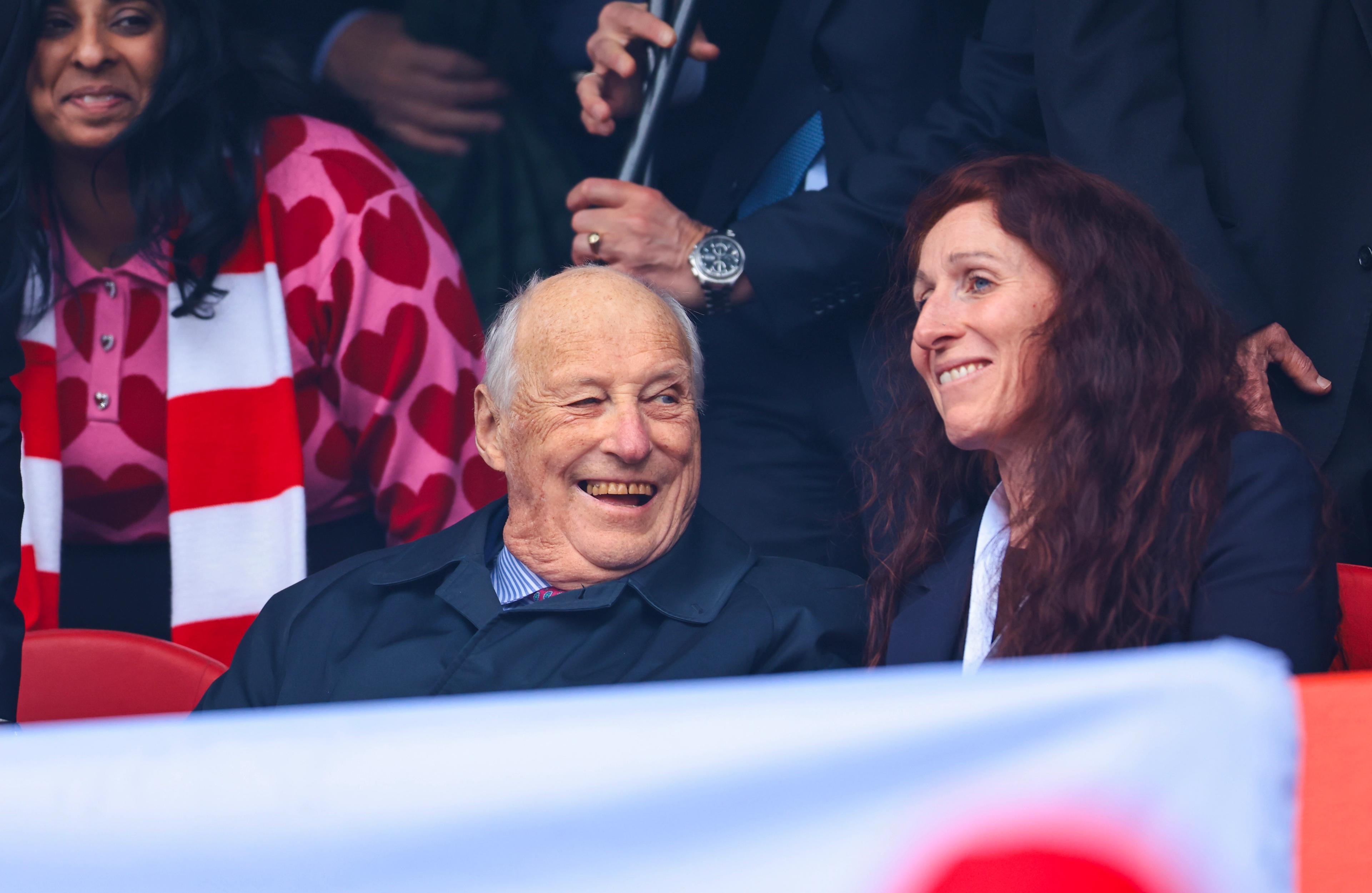 Kong Harald og Lise Klaveness smiler bredt fra tribunen.