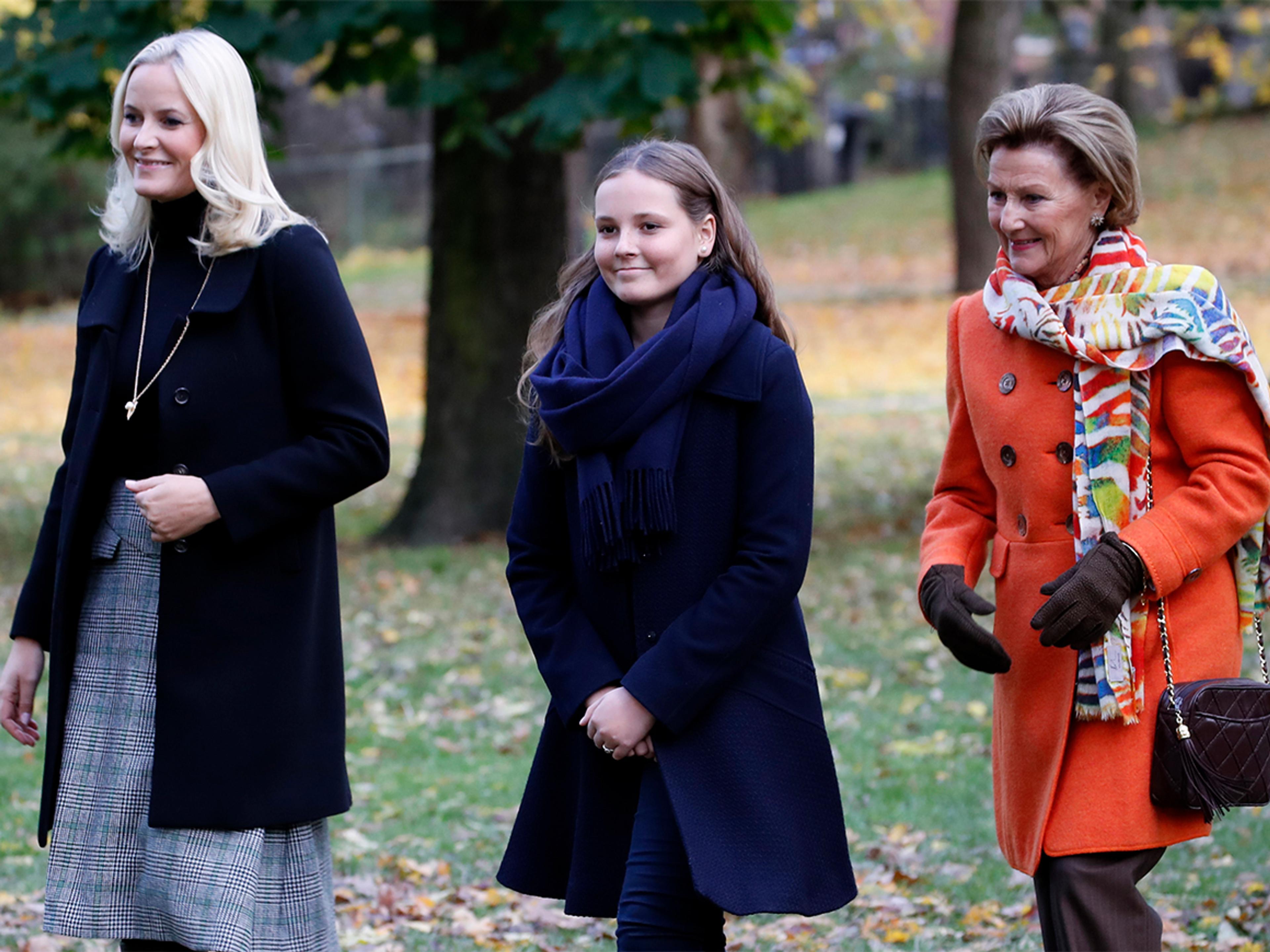 Dronning Sonja, Kronprinsesse Mette-Marit og Prinsesse Ingrid Alexandra kommer gående sammen gjennom parken, smilende.