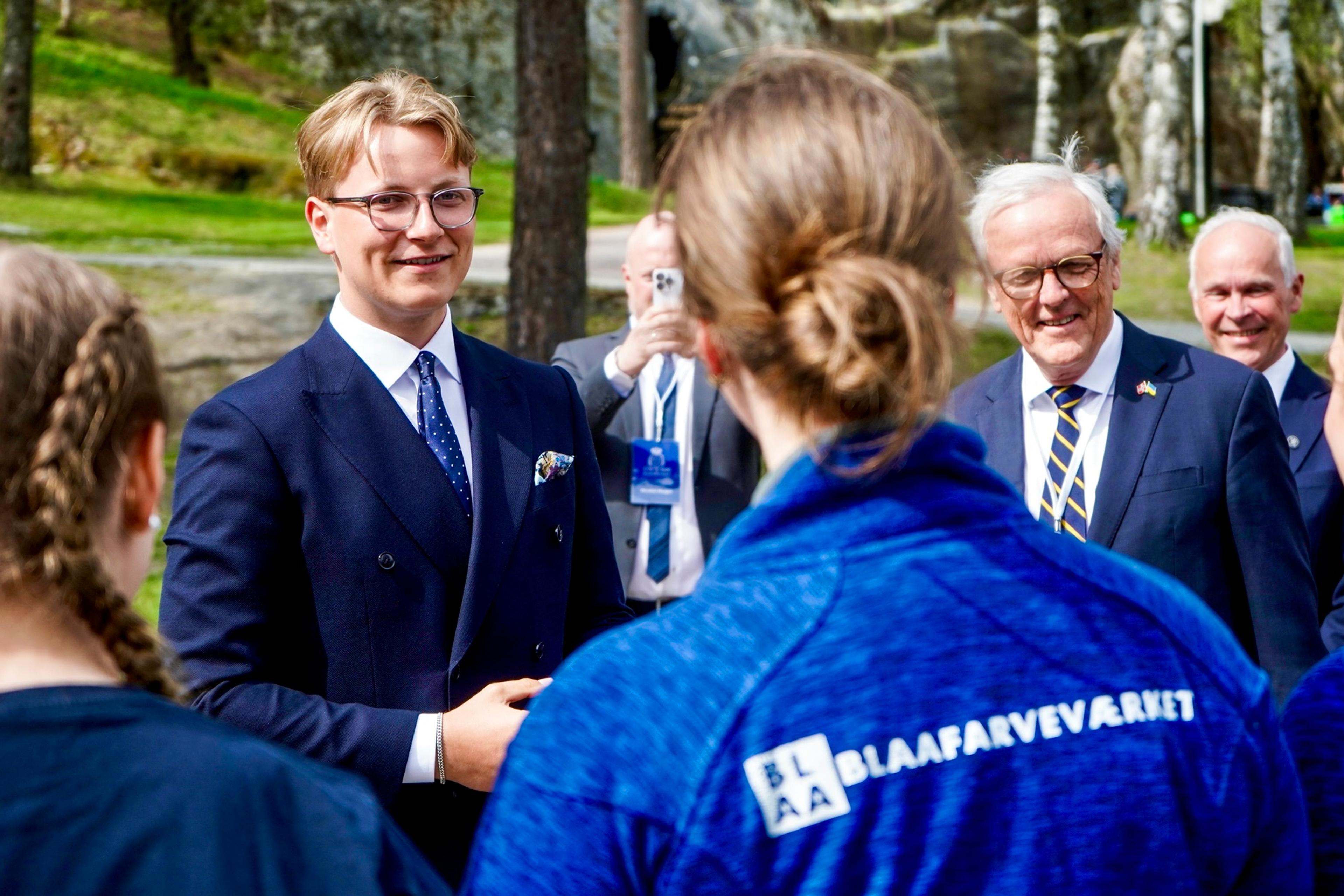 Prinsen smiler til unge representanter for Blaafarveværket, som står med ryggen til i samtale med Prinsen.