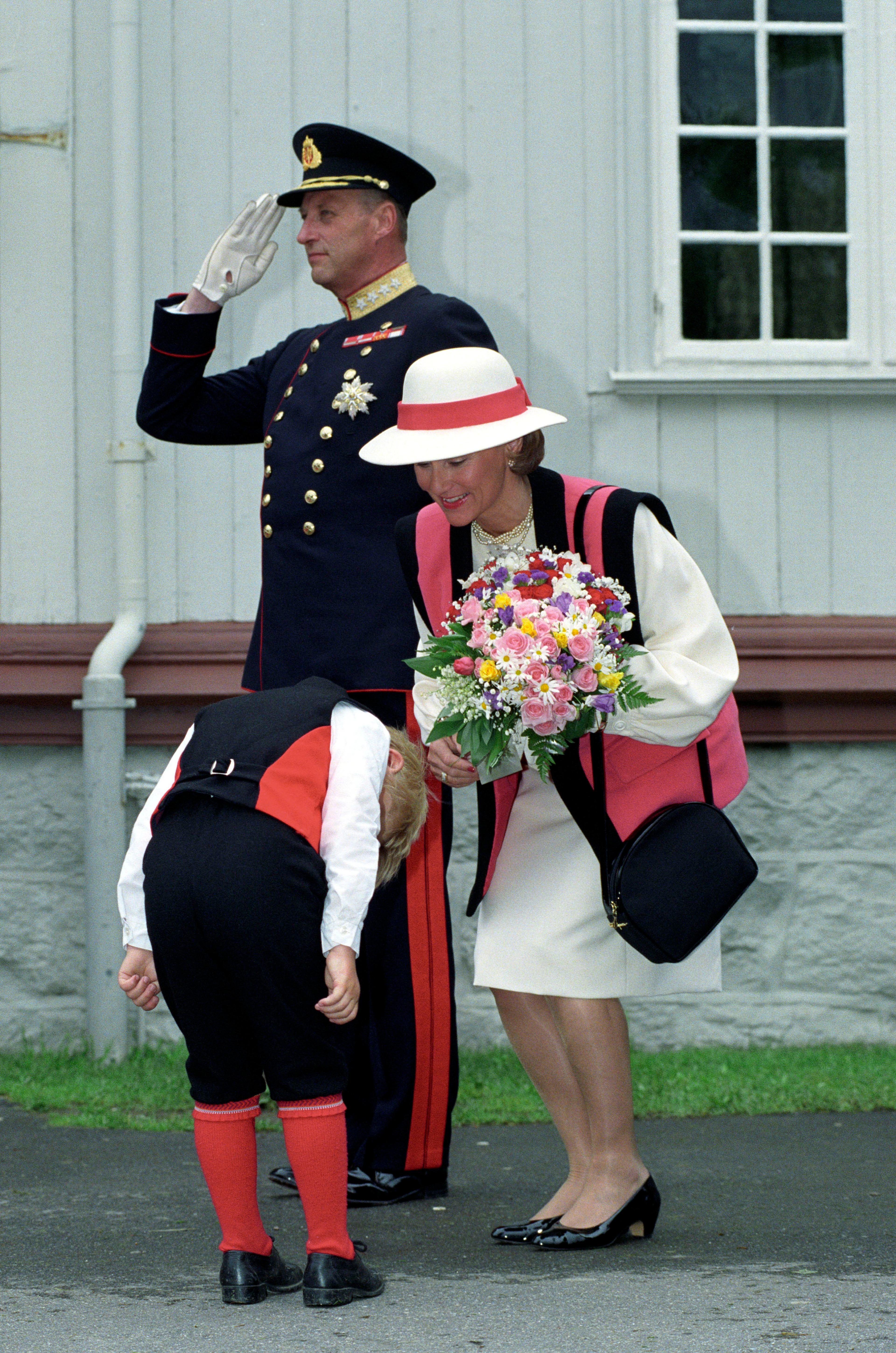 En liten gutt bukker dypt for Dronningen etter å ha gitt henne blomster.