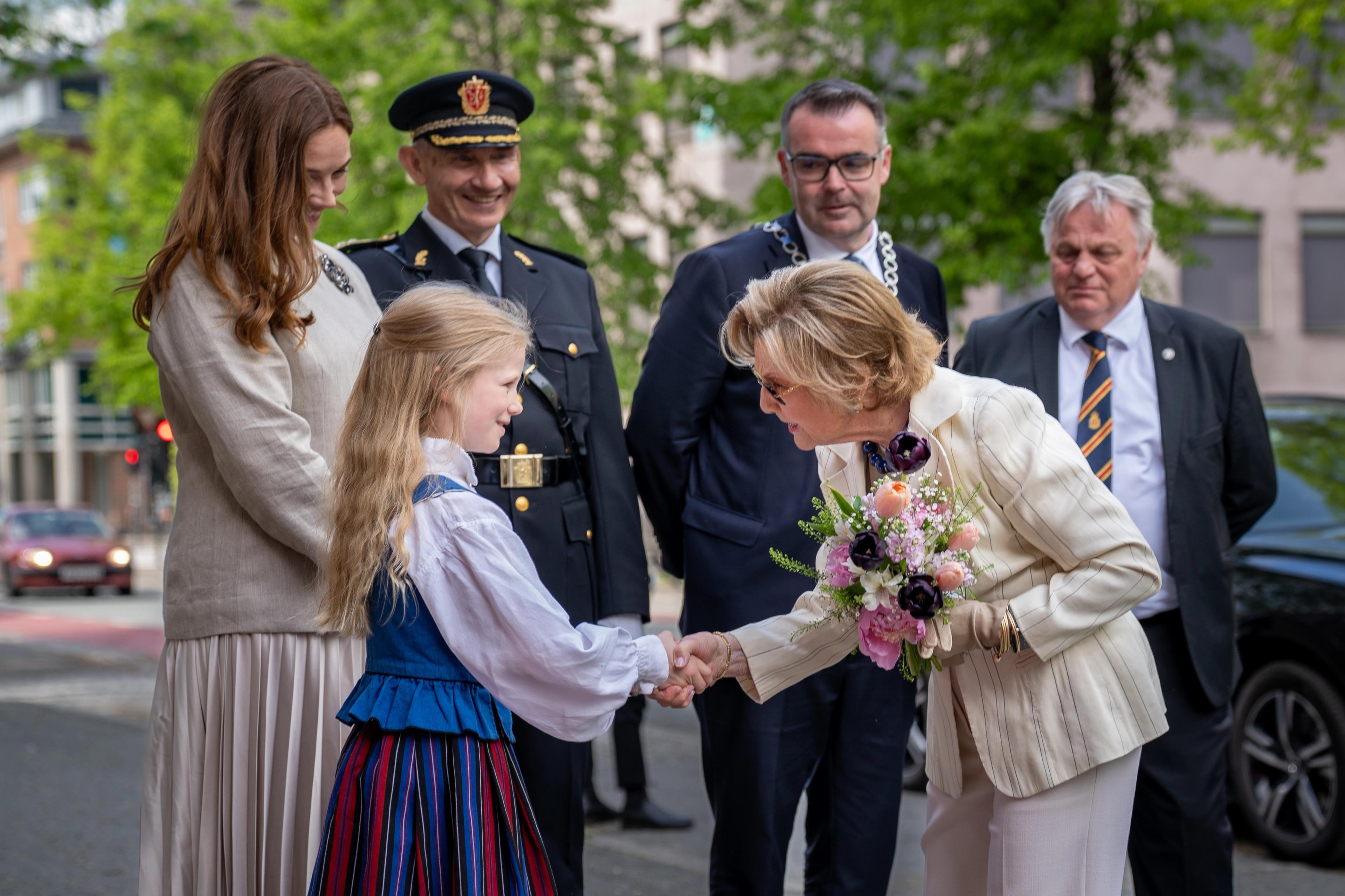 Dronning Sonja får blomster av Klara, mens museumsdirektør, politimester, ordfører og konstituert statsforvalter står rundt.